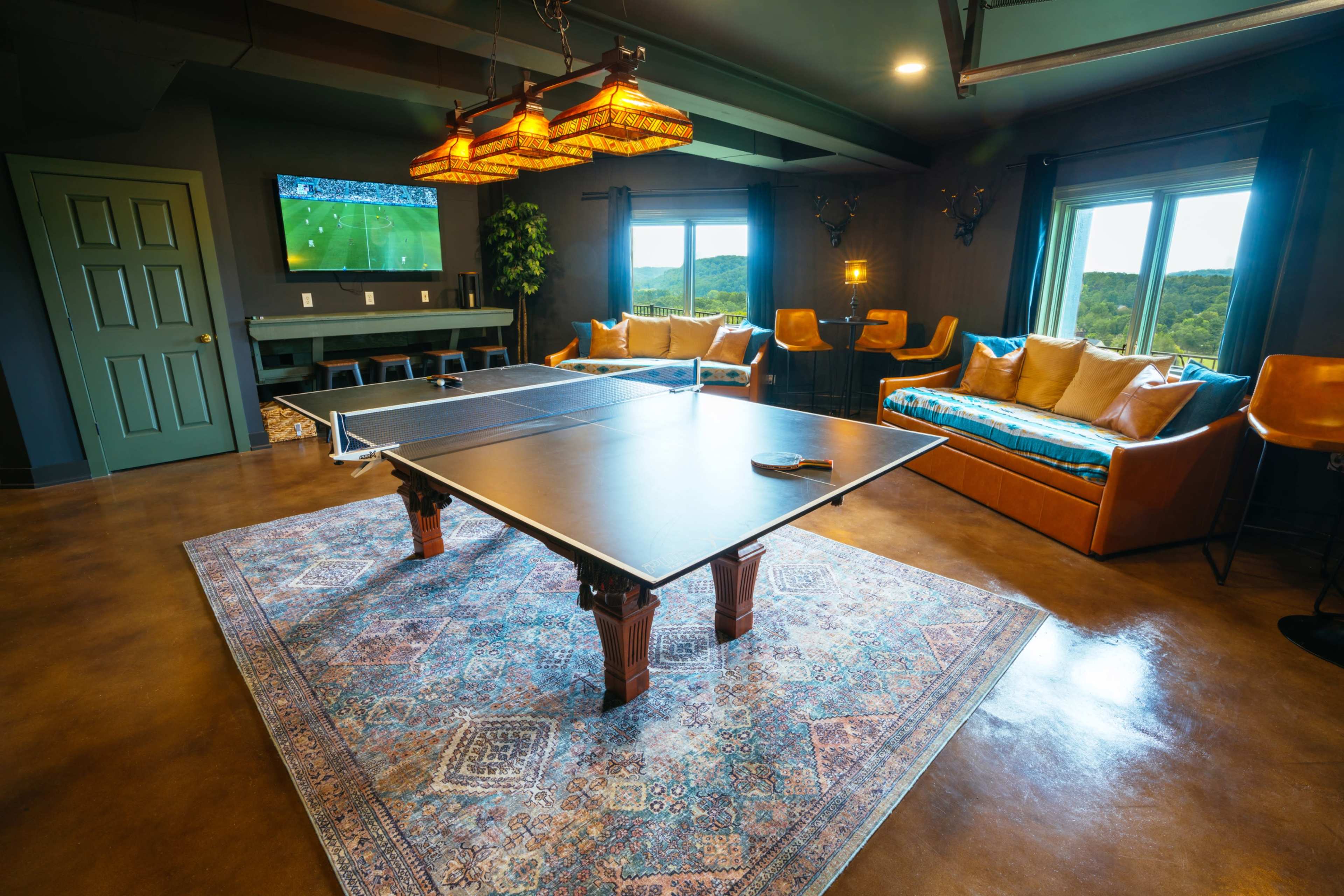 The image shows a recreational room featuring a ping pong table, a television mounted on the wall, and comfortable seating areas.
