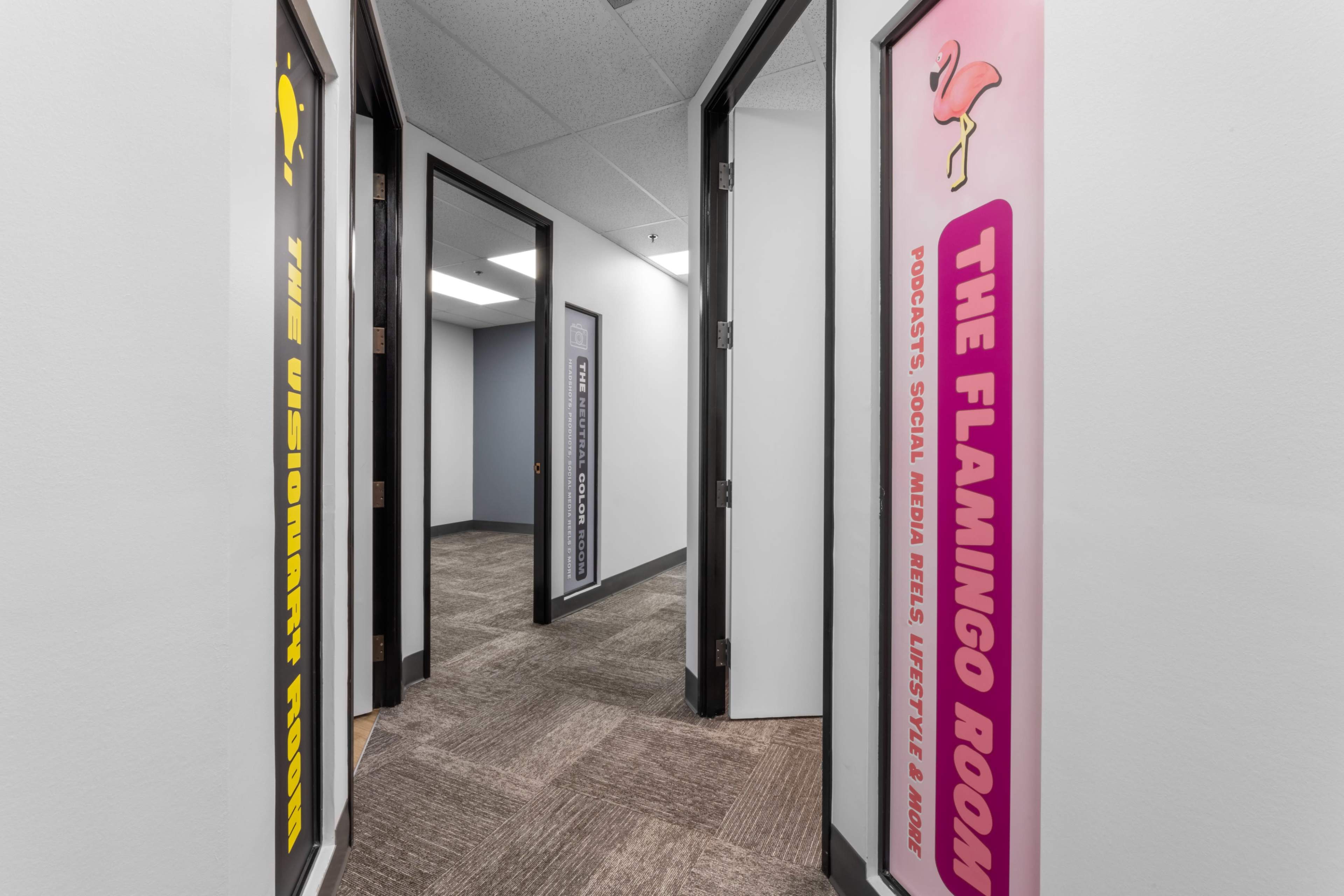 The image shows a hallway with two open doors featuring colorful signs labeled "The Visionary Room" and "The Flamingo Room."