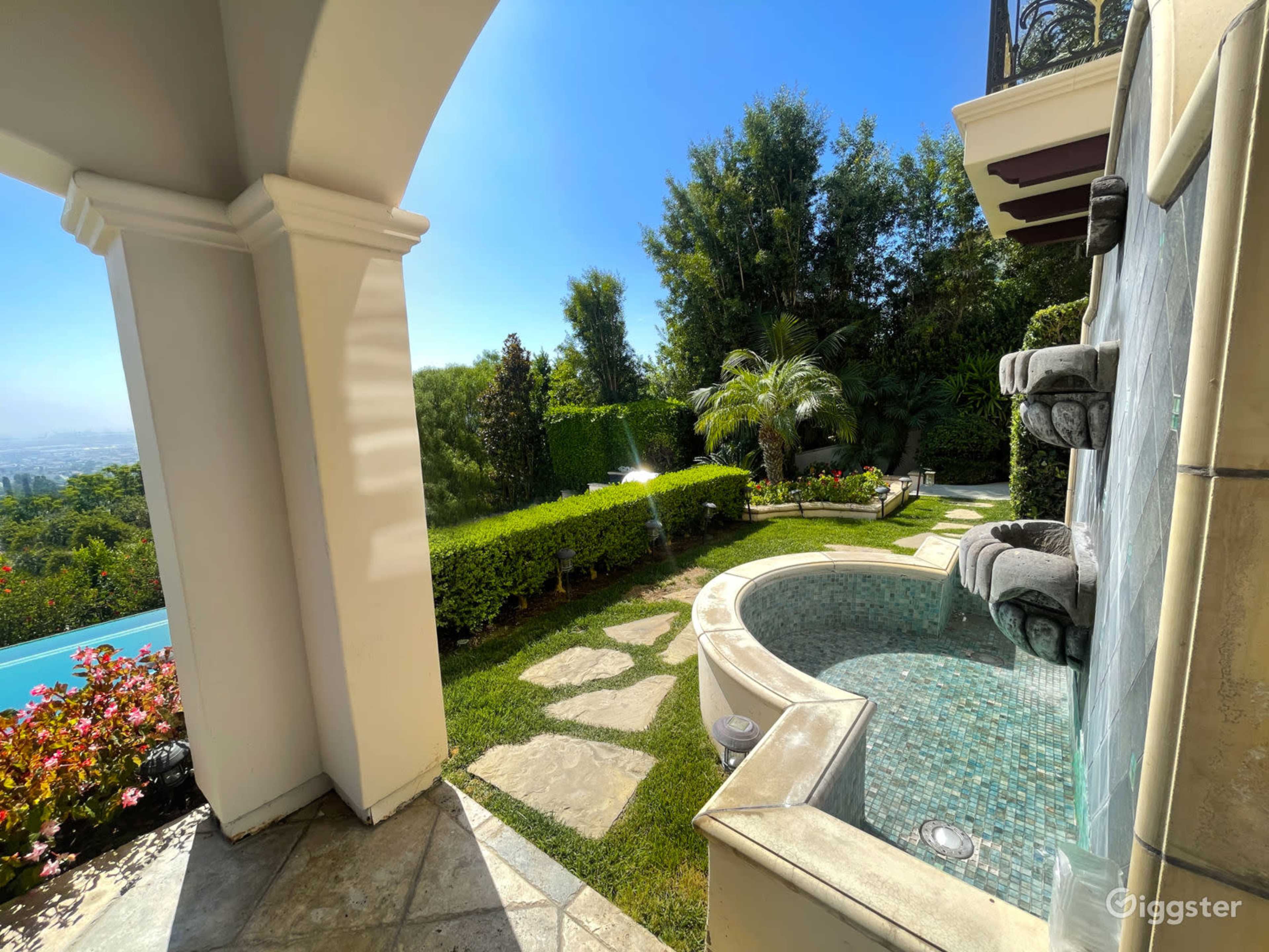A landscaped outdoor area featuring a small pool with a fountain and surrounding greenery.