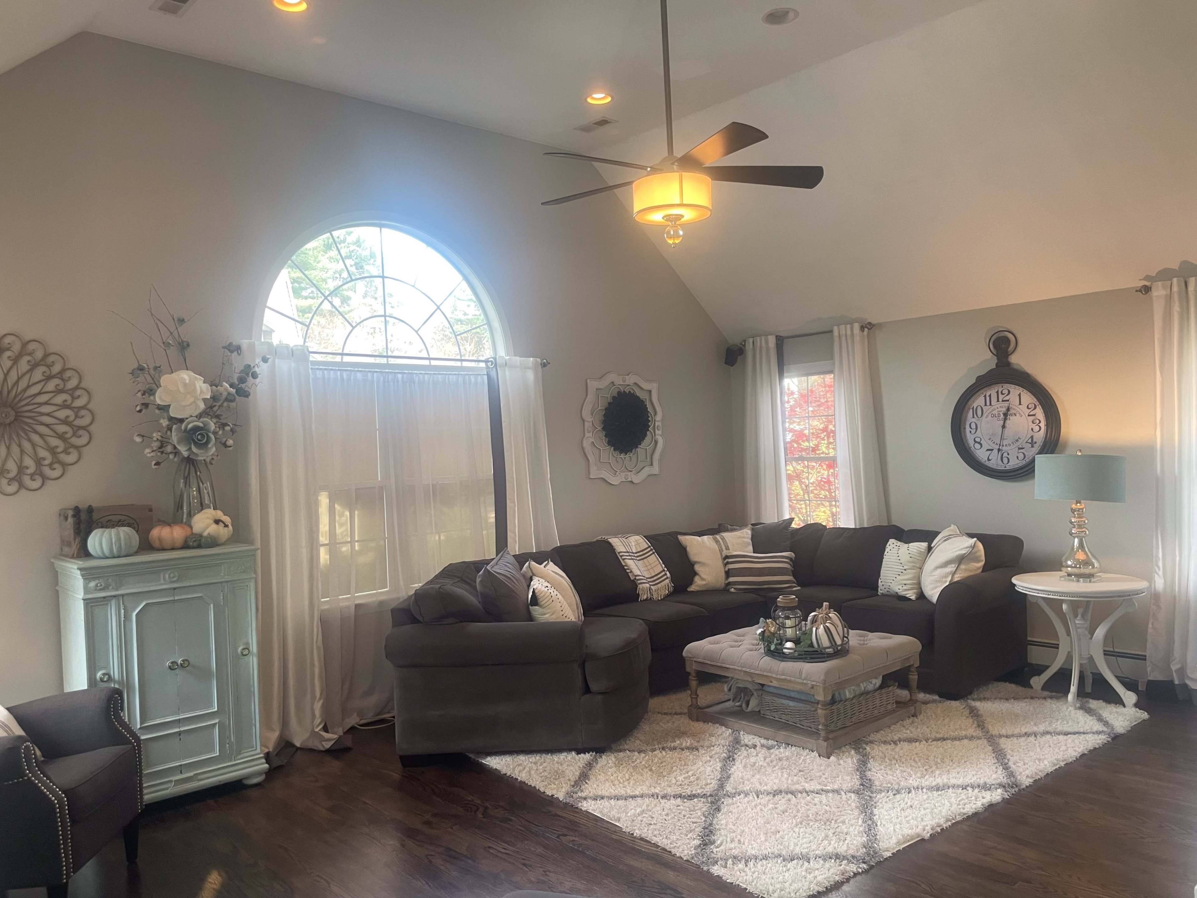 A living room with a large window, a sectional sofa, a coffee table on a rug, and decorative accents.