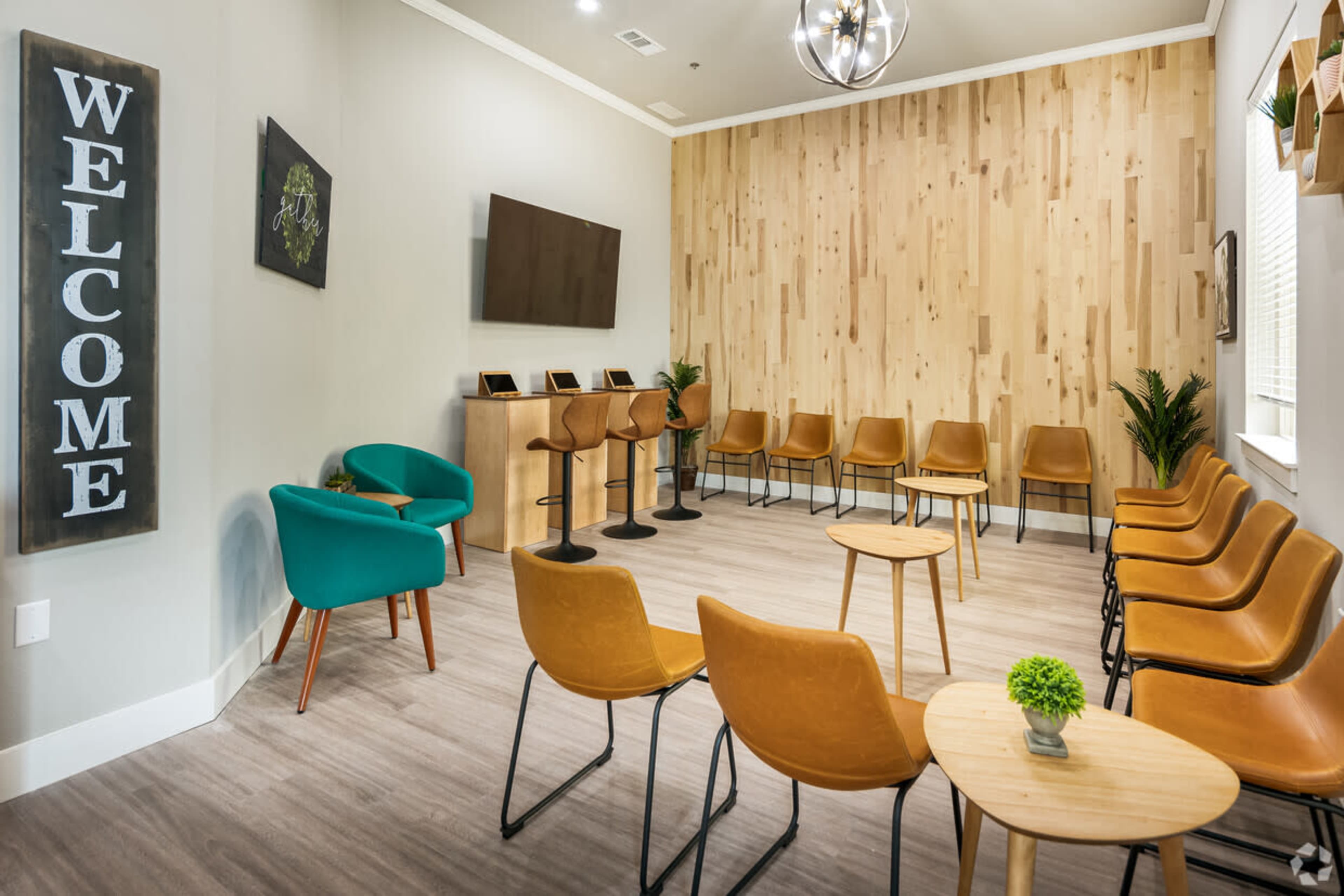 A welcoming waiting room features a mix of brown and teal seating arranged around small wooden tables against a wooden accent wall.
