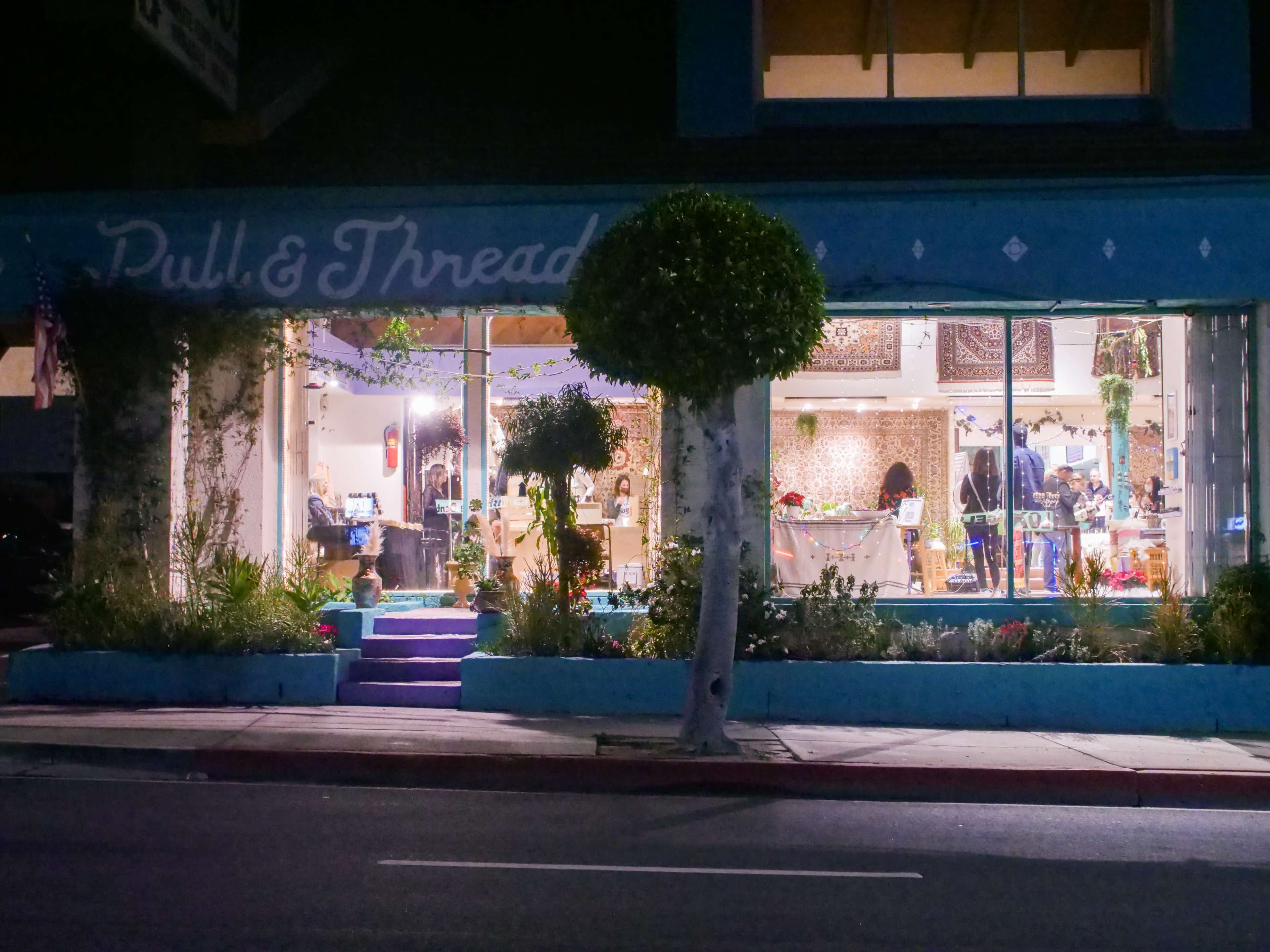 A brightly lit store named "Purl & Thread" features displays of fabric and craft supplies, visible through large front windows, with customers browsing inside.