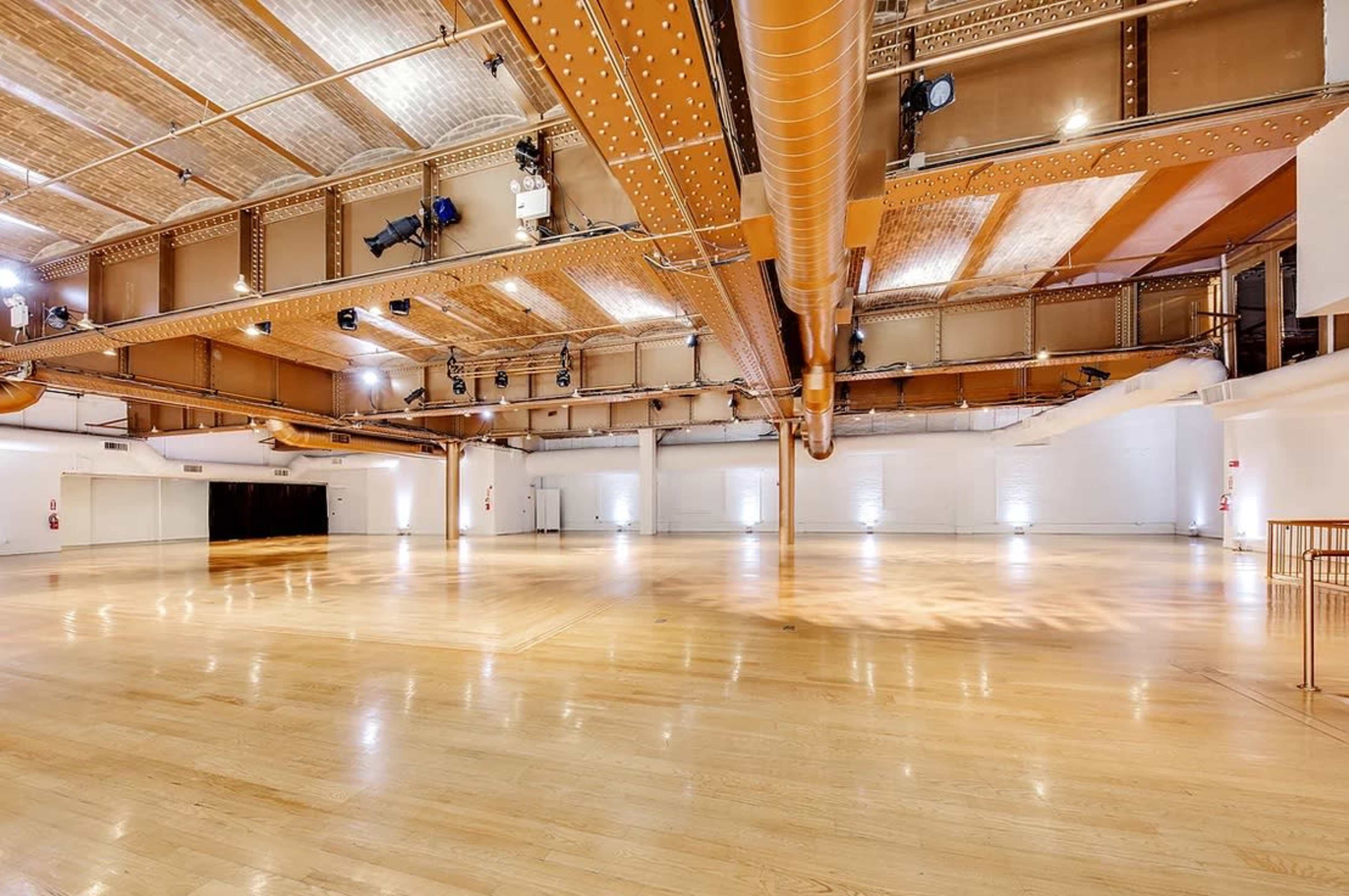 A spacious, well-lit interior with wooden flooring and exposed metal beams.