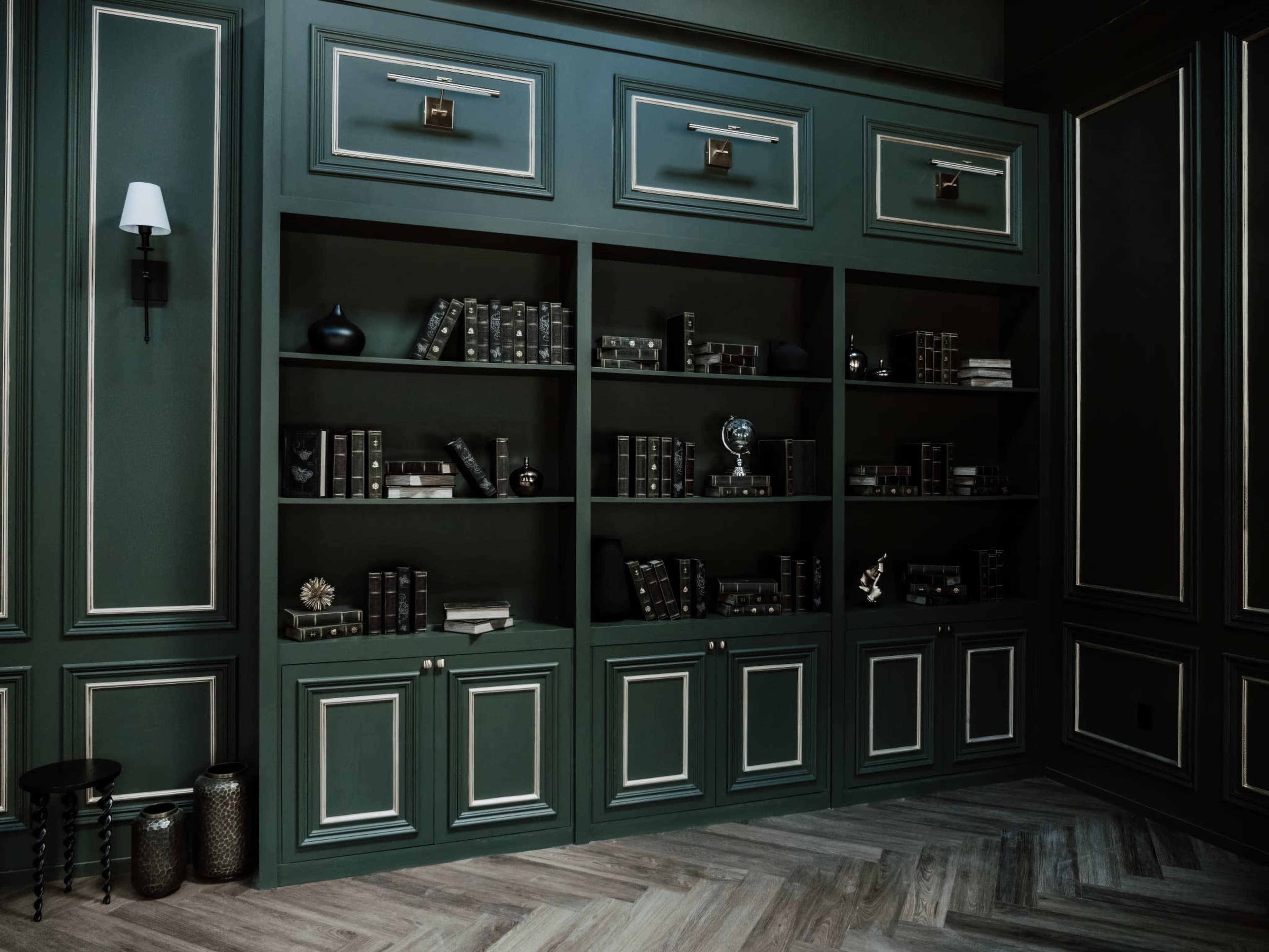 A dark green room with a large bookshelf filled with books and decorative items.