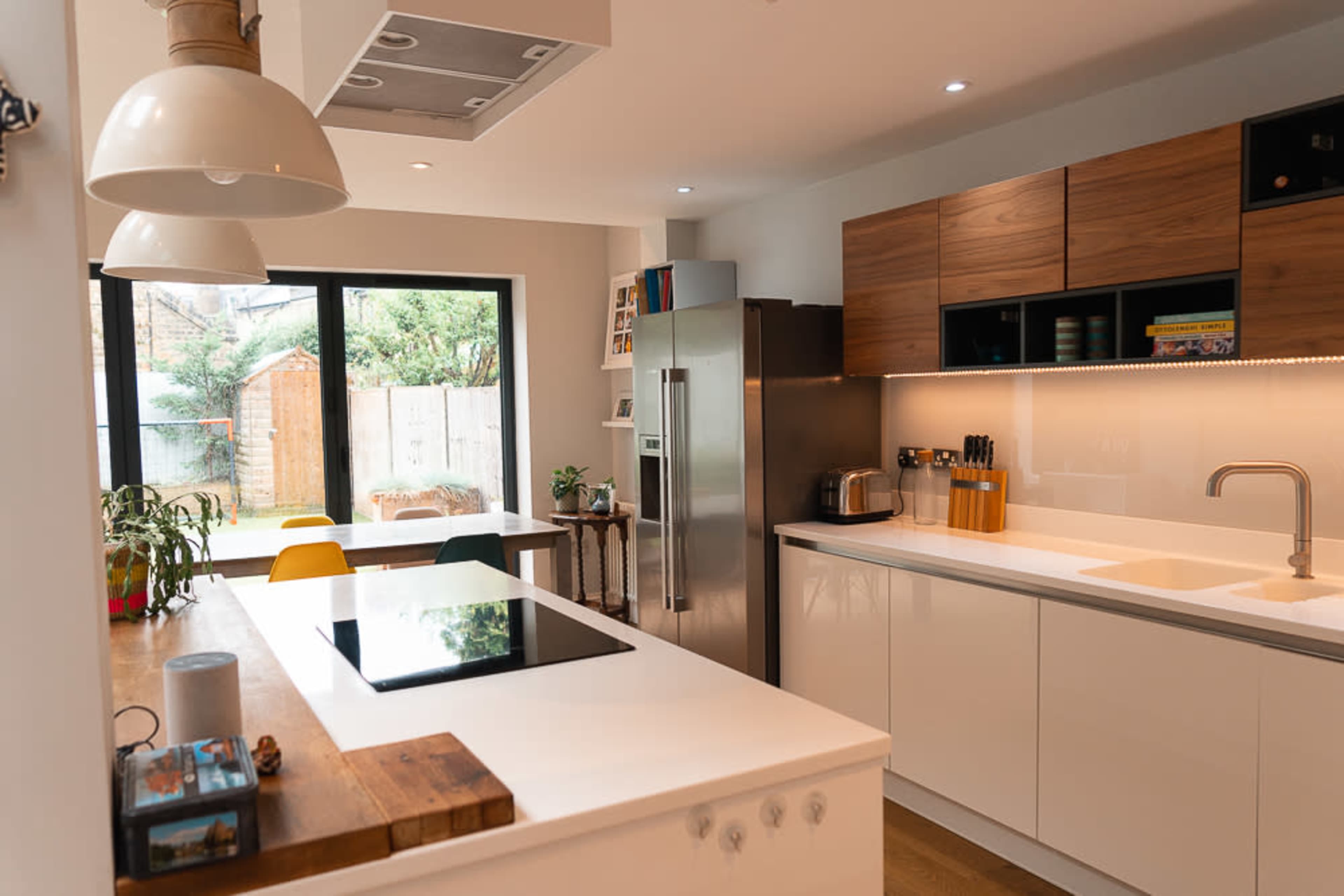 The modern kitchen features a central island with an induction cooktop, sleek cabinetry, and large windows overlooking a garden.