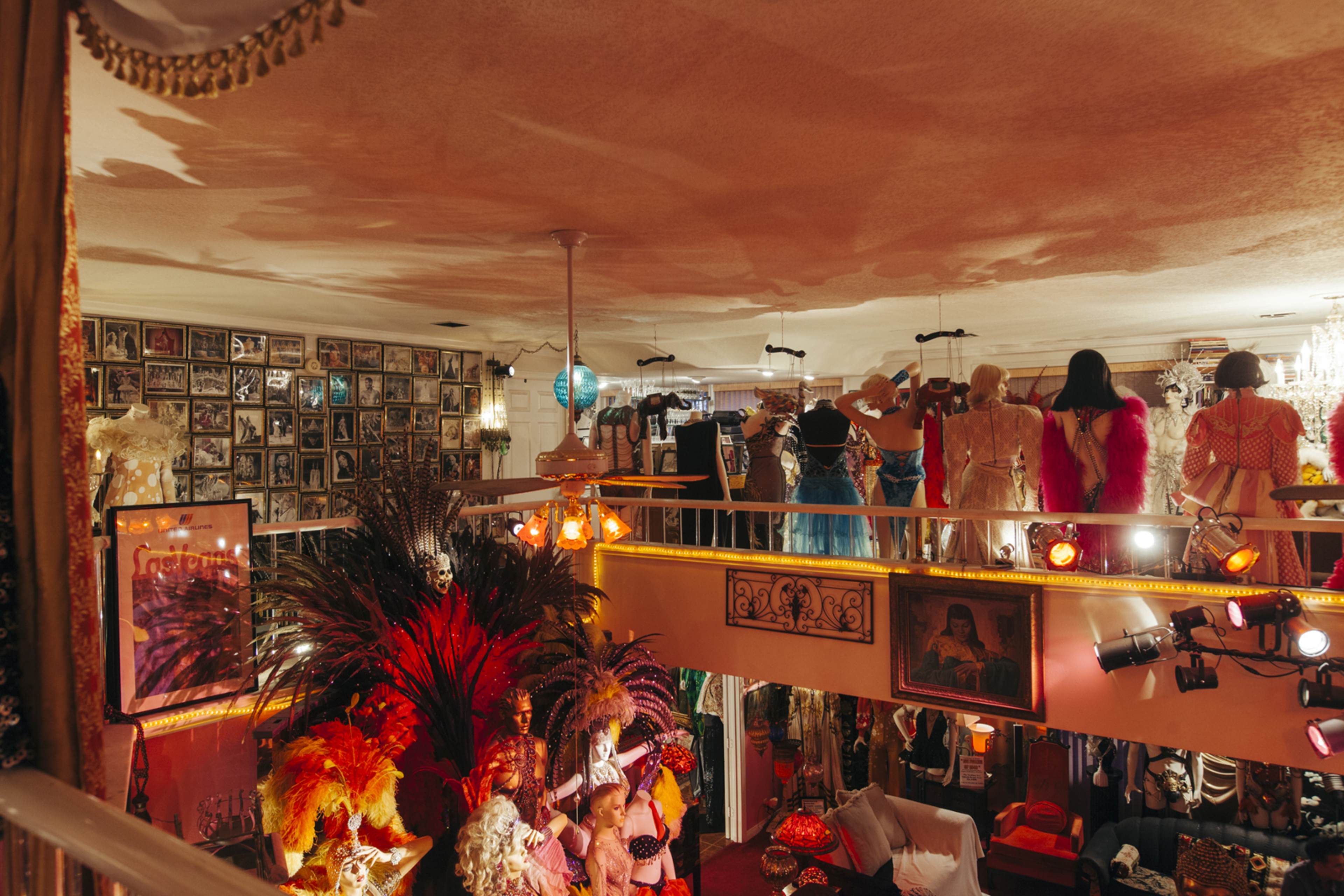 The scene shows a colorful dress shop with costumes and mannequins displayed on a lower level, while people in various outfits can be seen on a balcony above.