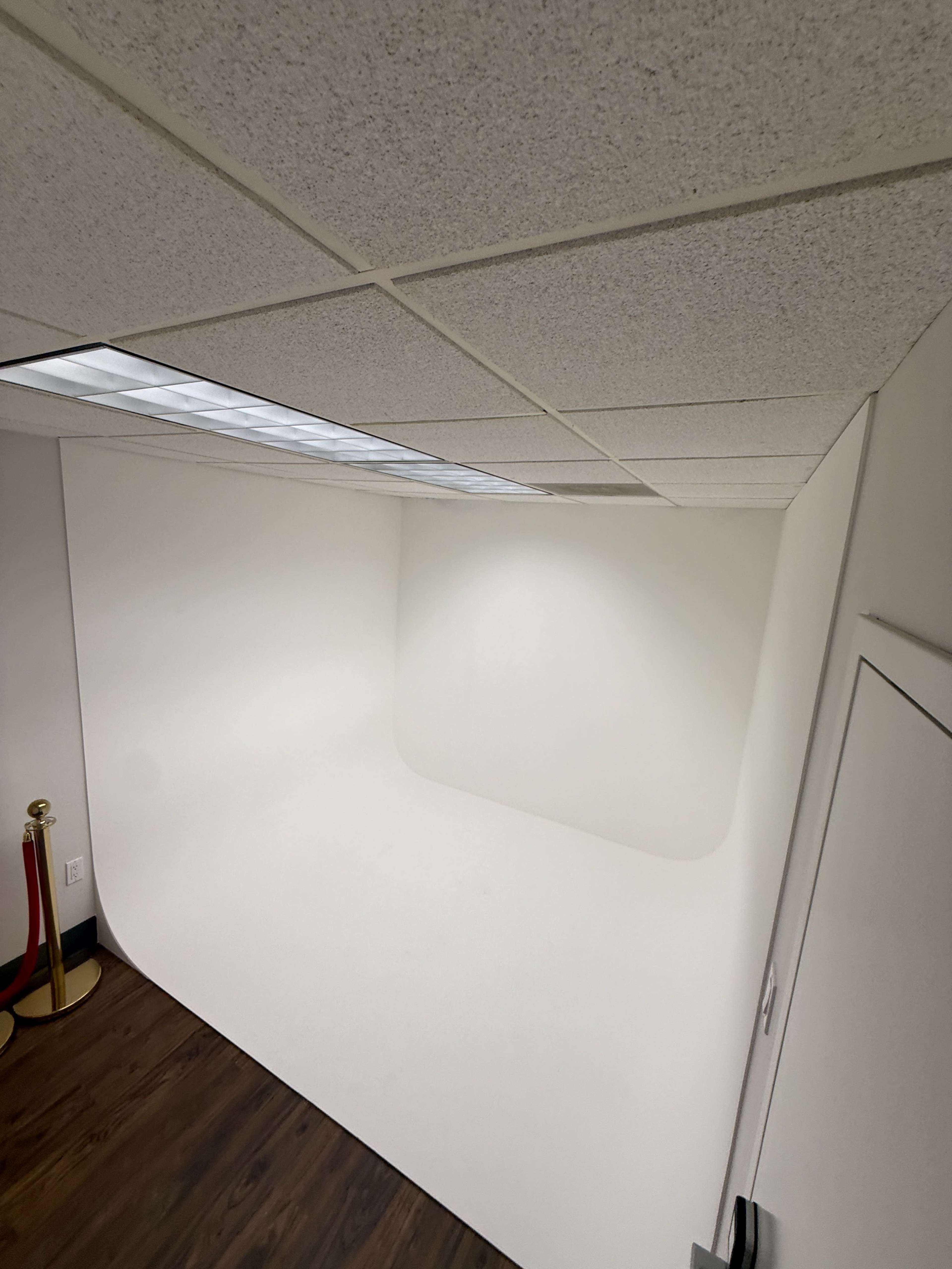 The image shows a minimalistic photo studio with a seamless white backdrop and a smooth curved transition into the floor.
