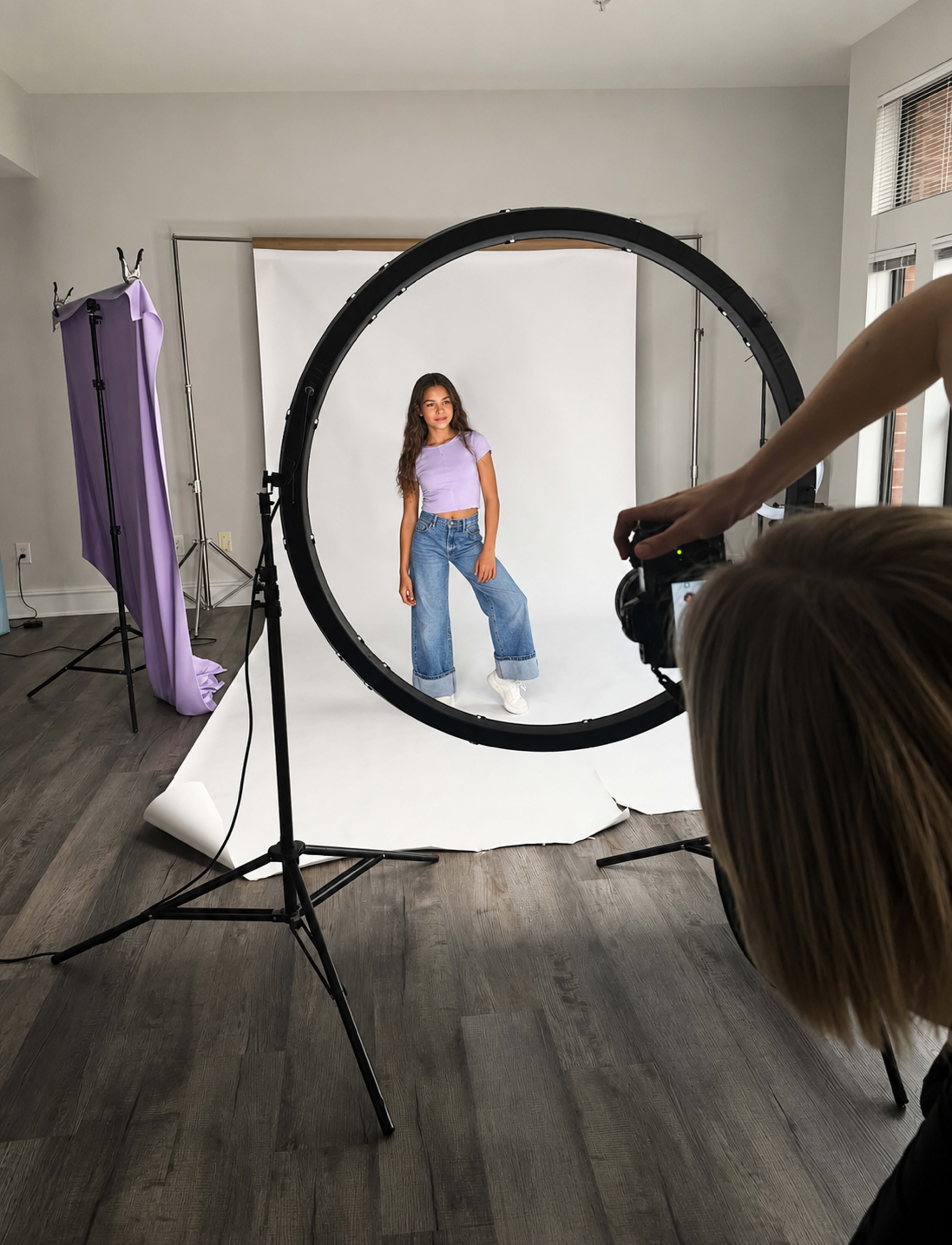 A photographer captures a model posing in front of a circular backdrop in a well-lit studio.