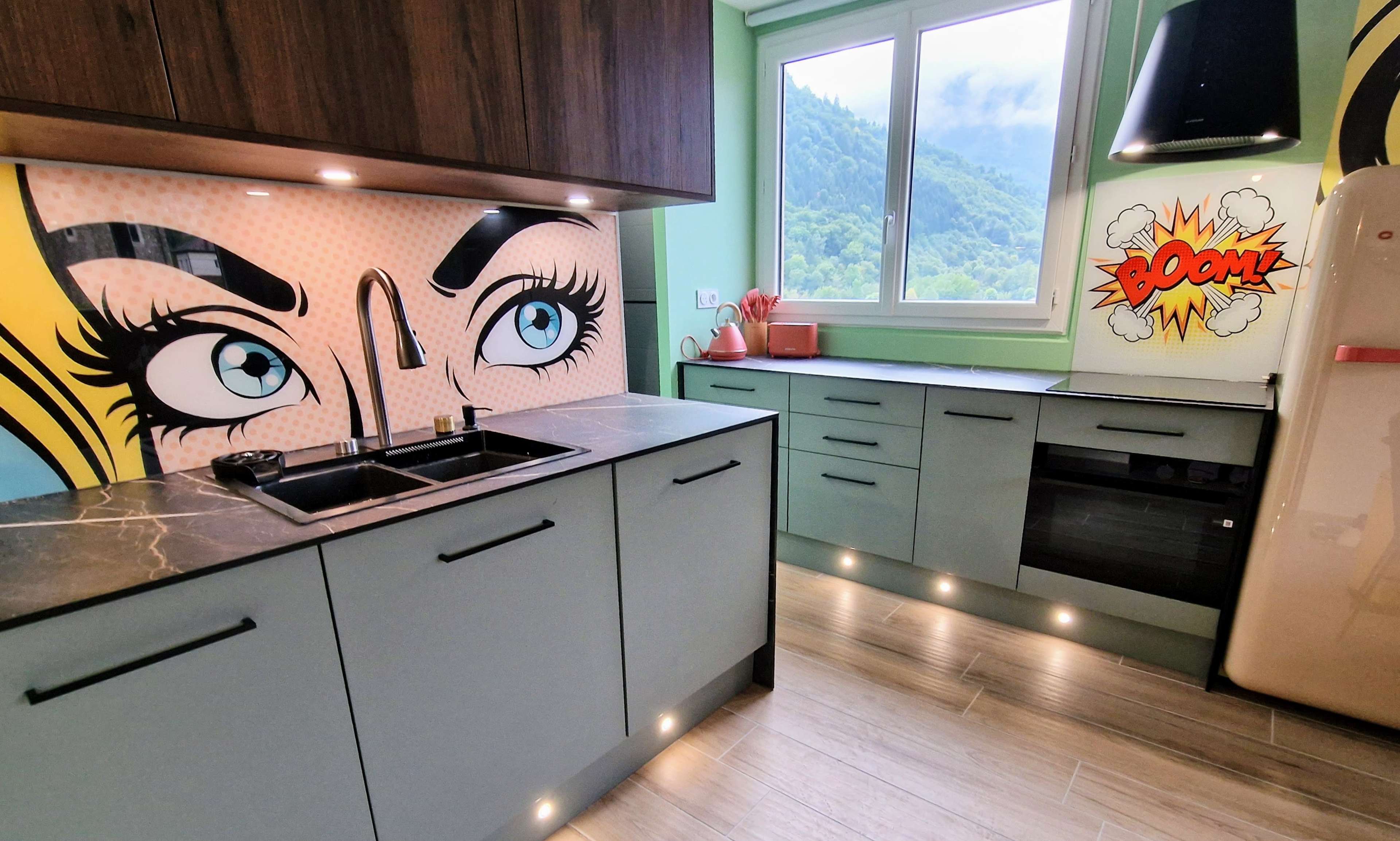 The kitchen features modern cabinetry with a striking graphic mural on the wall and large windows allowing natural light.