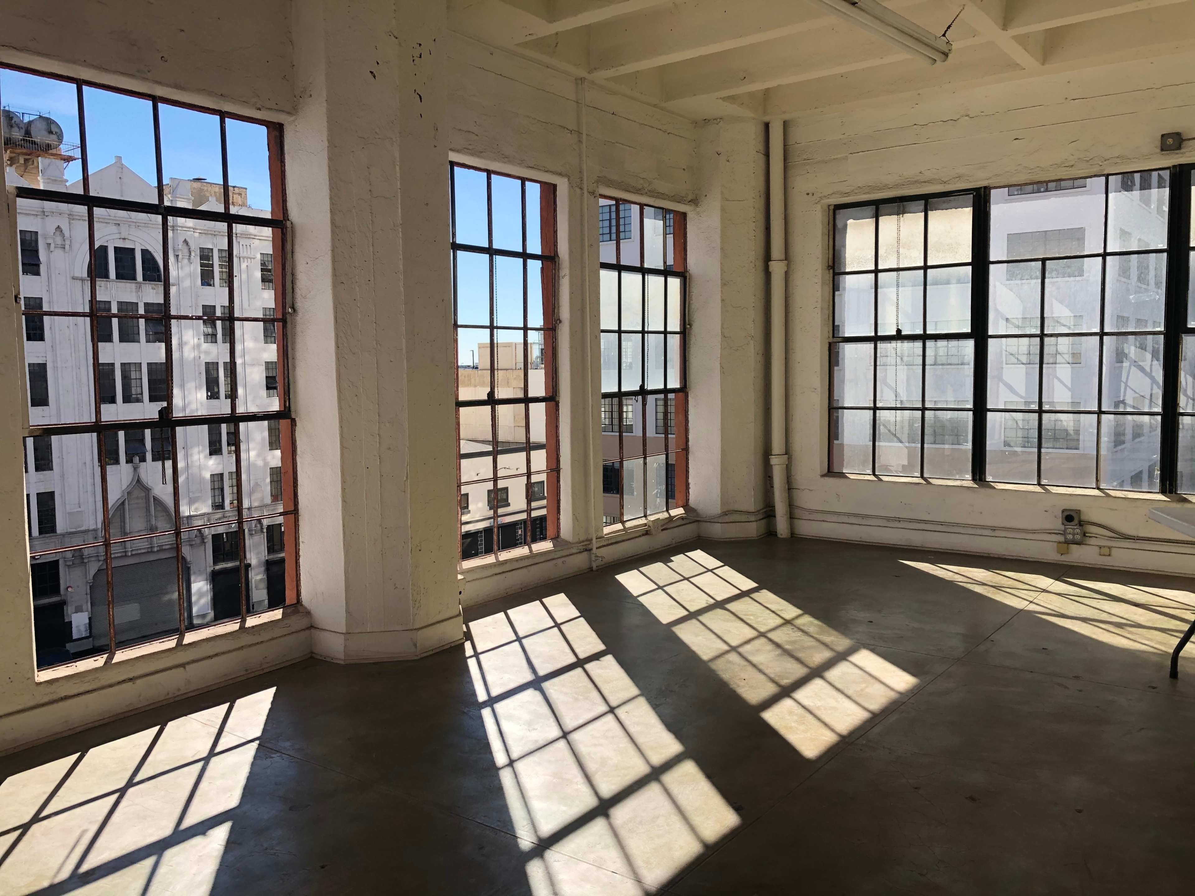 The room features large, industrial windows that cast elongated shadows across the concrete floor.