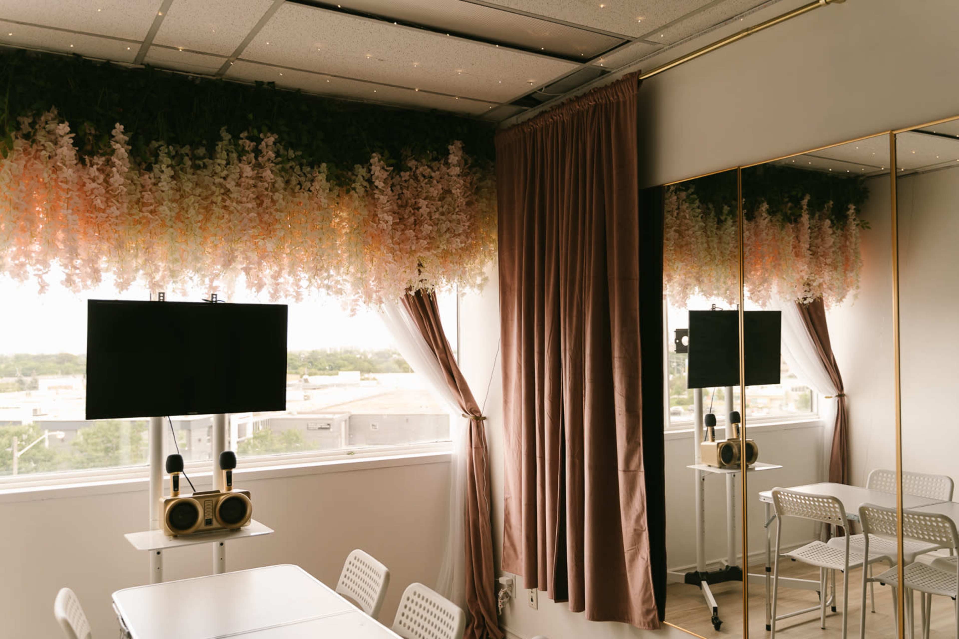 The image shows a modern meeting room with a floral ceiling decoration, a large TV mounted on the wall, and large windows with curtains.