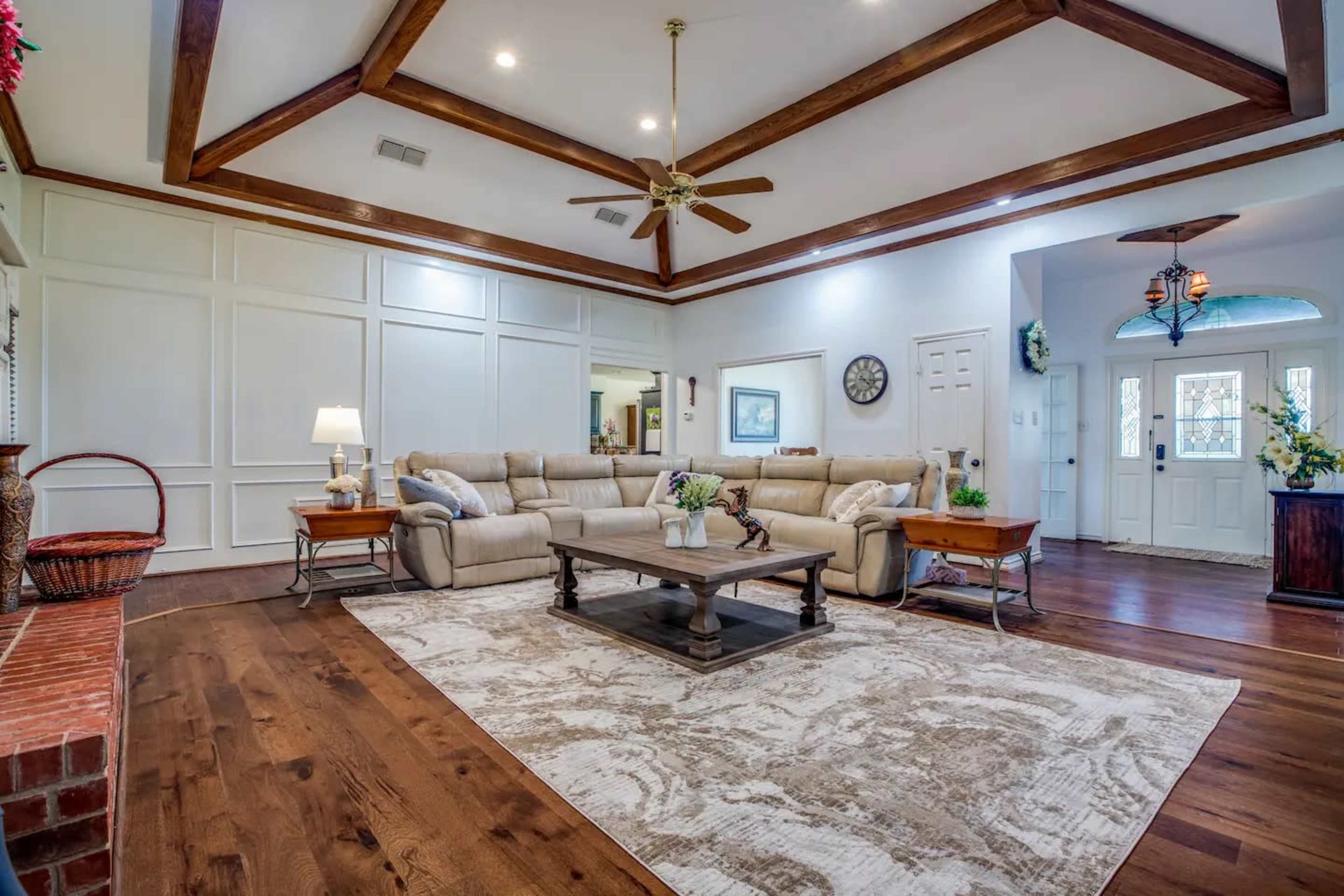 The living room features a coffered ceiling, a sectional sofa, a coffee table, and a front entryway with glass-paneled doors.
