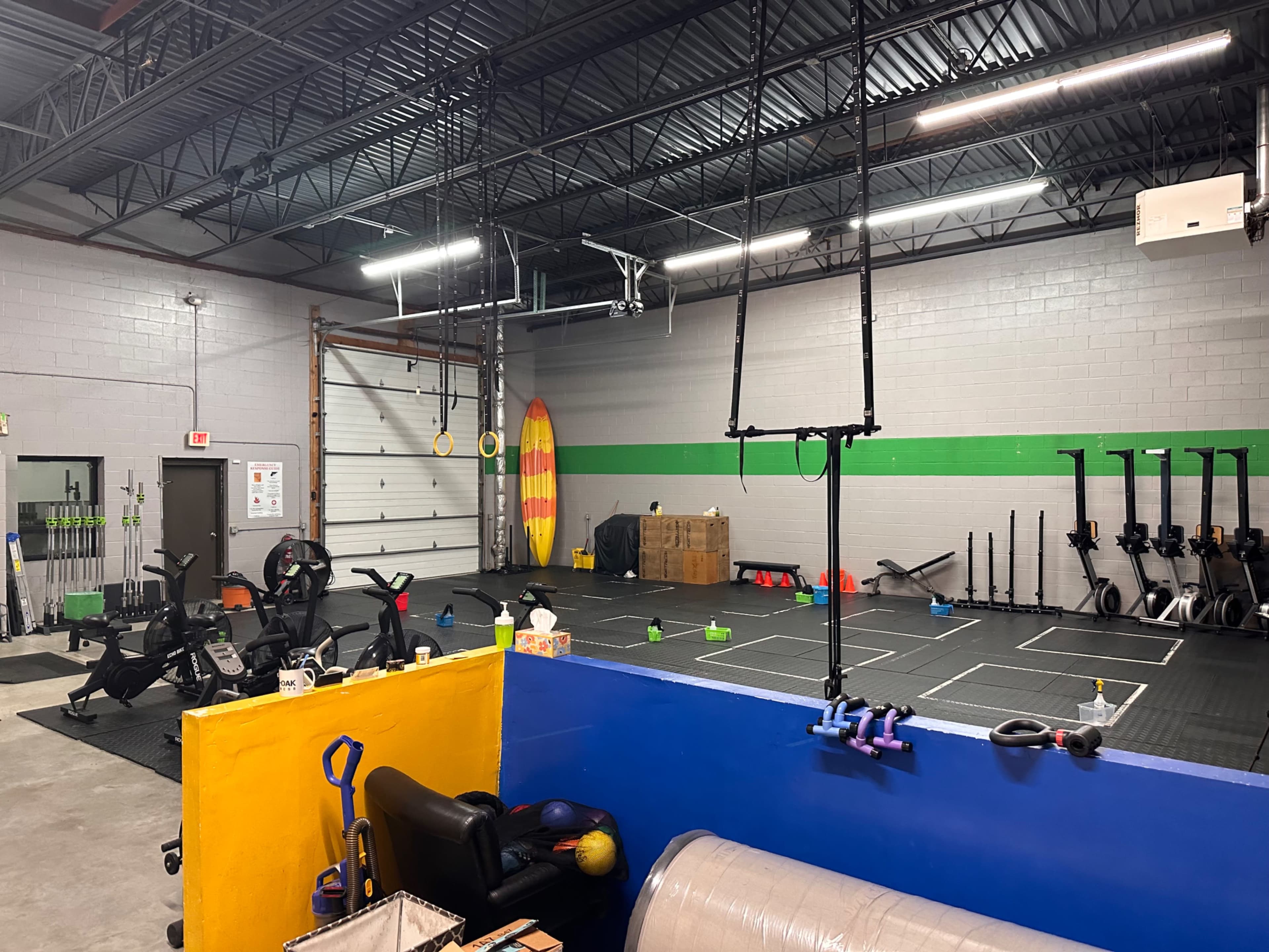 A spacious gym equipped with exercise machines, fitness equipment, and a designated area for various workout activities, including hanging rings and ropes.