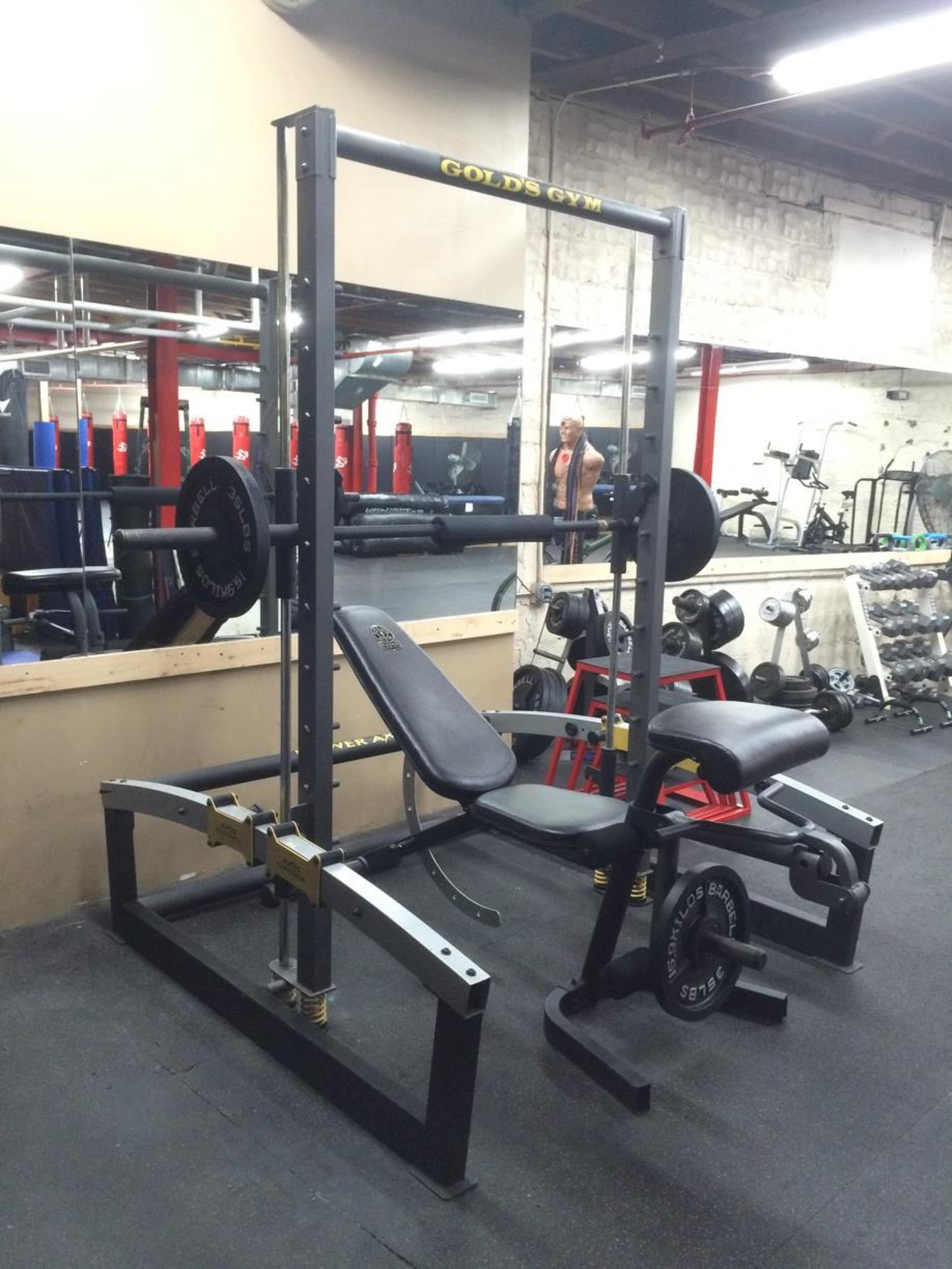 A gym setup featuring a weight bench and barbell rack with weights, situated in a fitness facility.