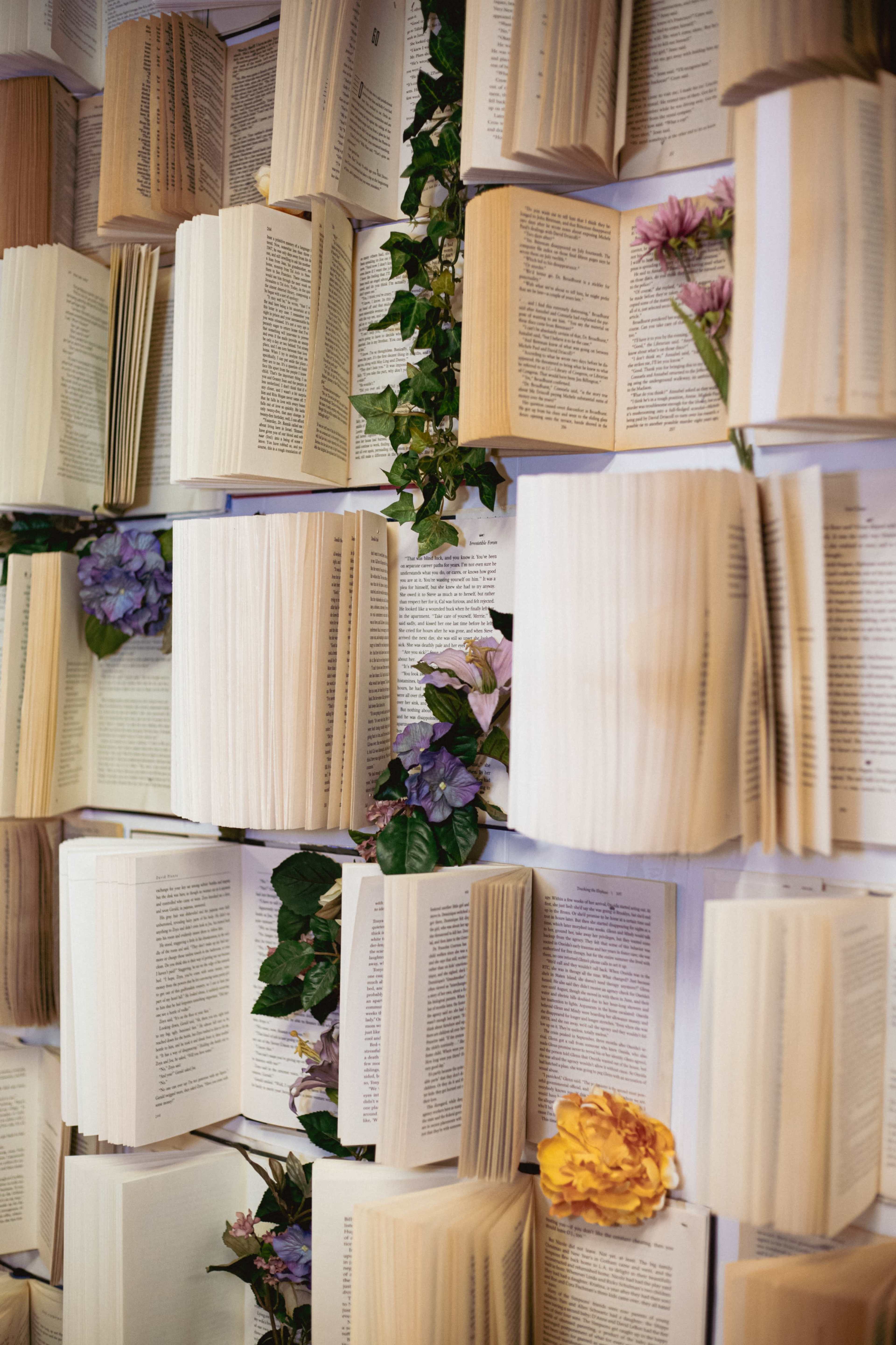 A wall decorated with open books, interspersed with green vines and flowers.
