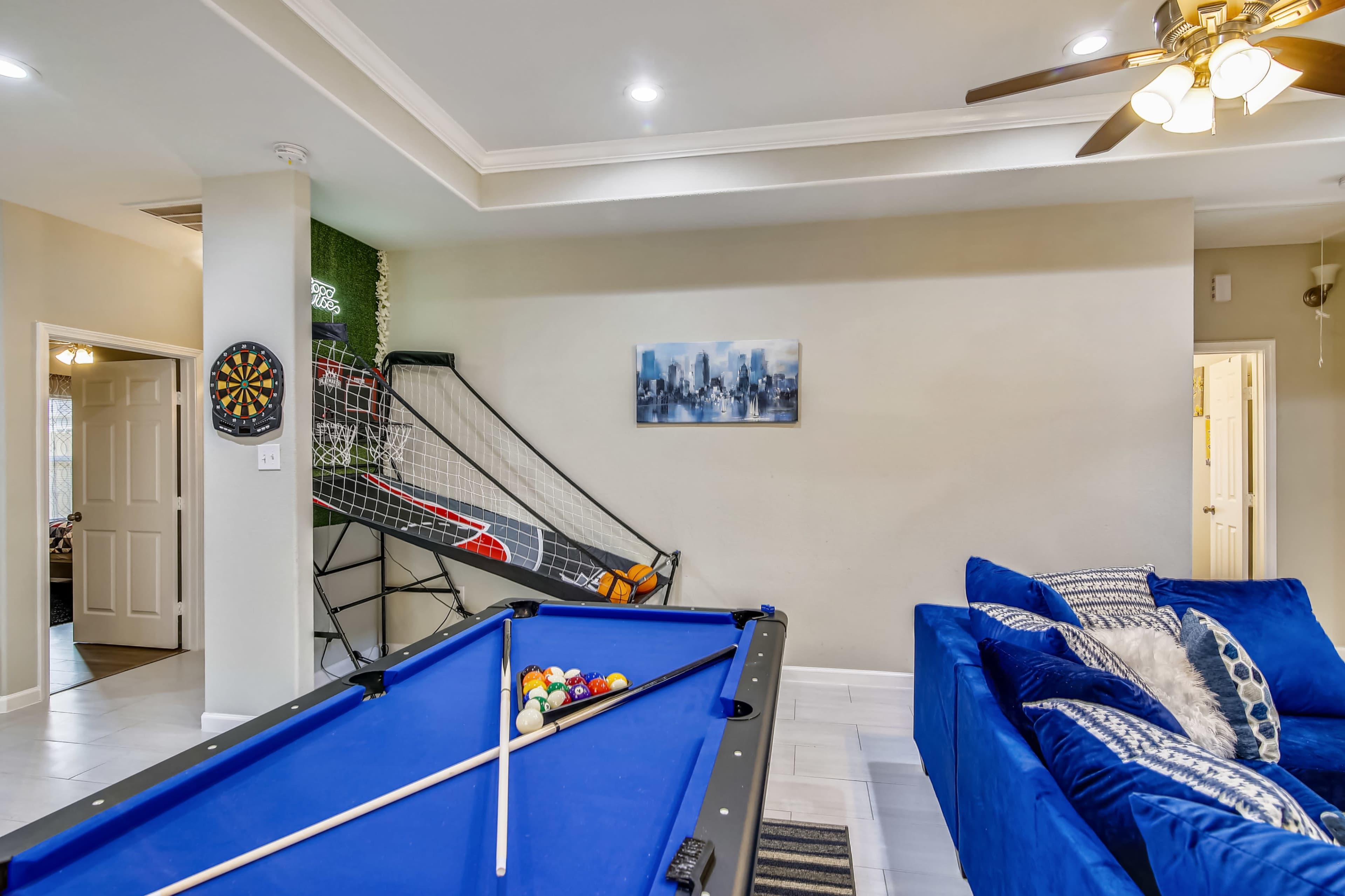 A game room featuring a blue pool table, a dartboard on the wall, and a soccer goal net in the background.