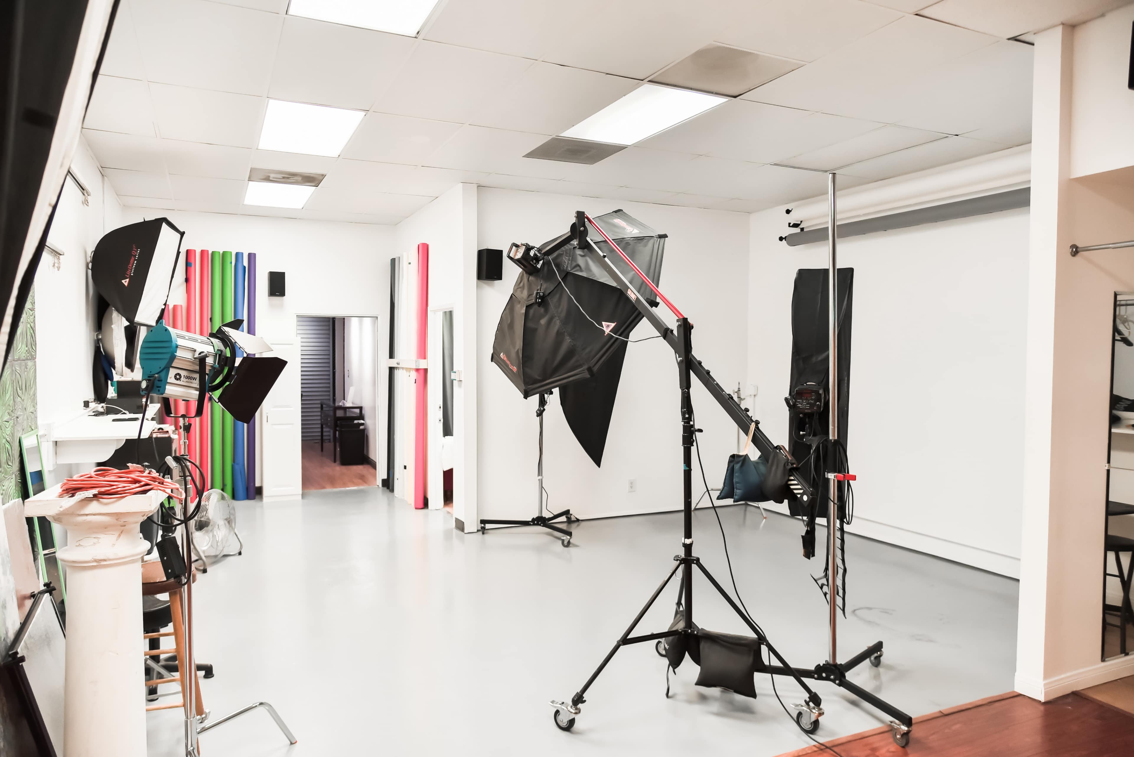 A photography studio equipped with lighting setups, backdrops, and a camera on a tripod.