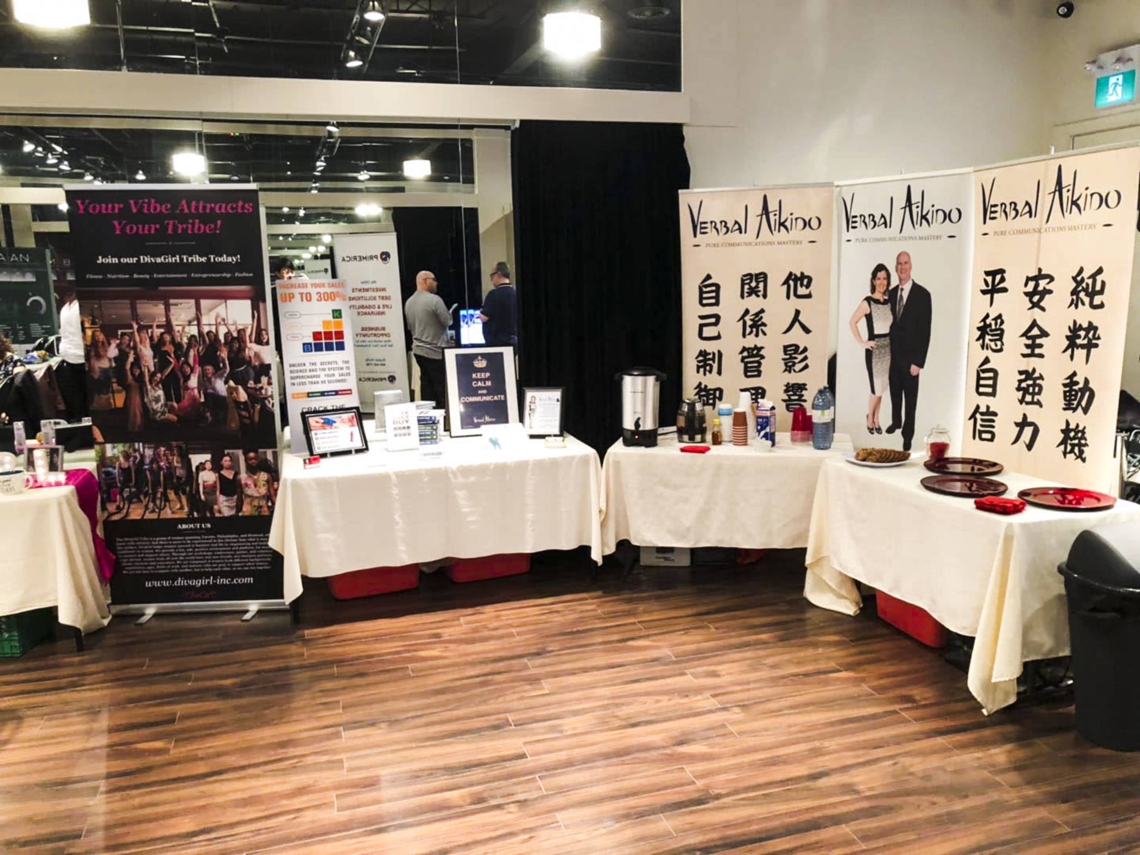 A display area with two tables featuring promotional materials and banners for a martial arts program and an event.