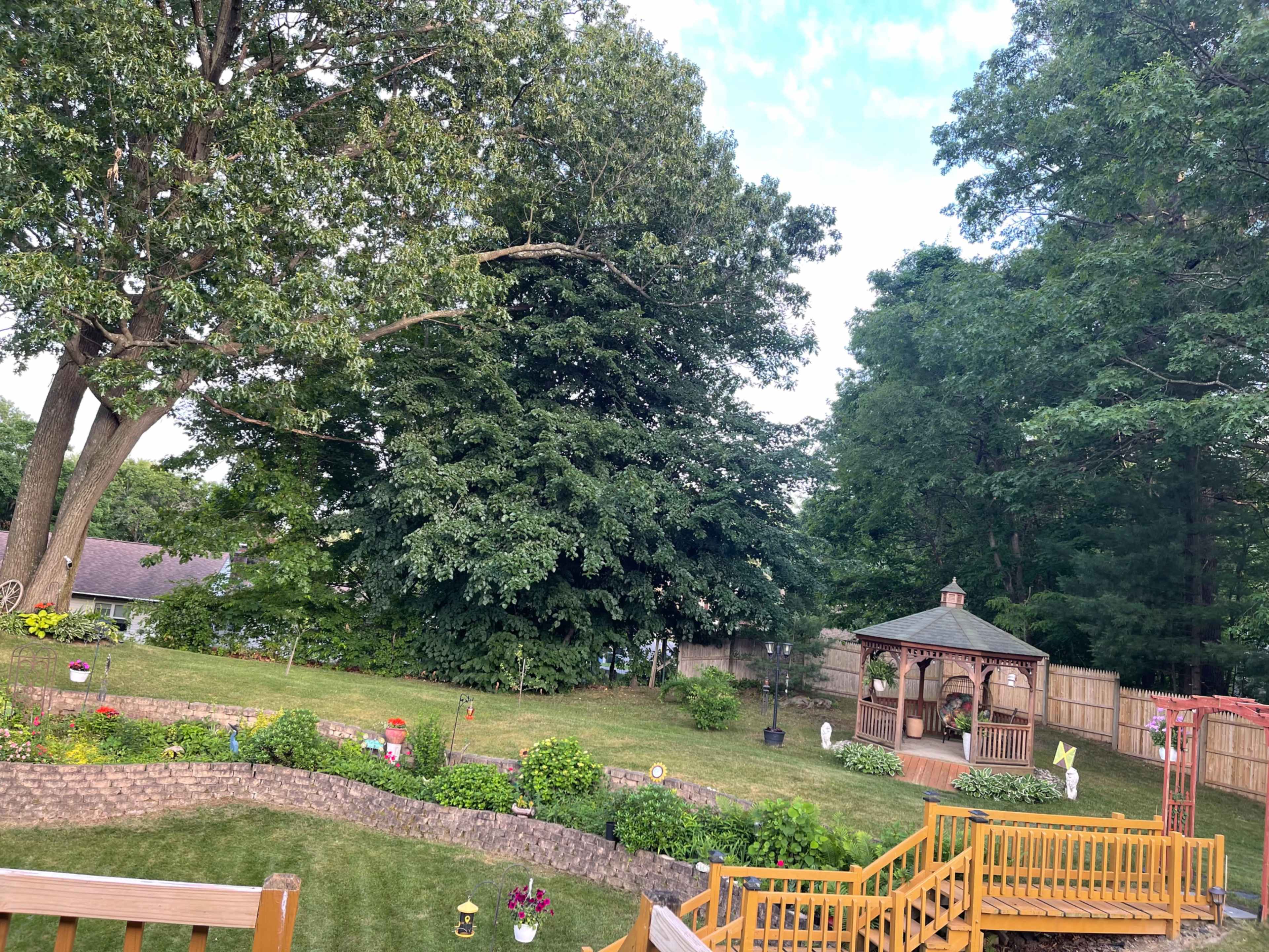 A spacious backyard features a gazebo, well-maintained grass, and several trees.