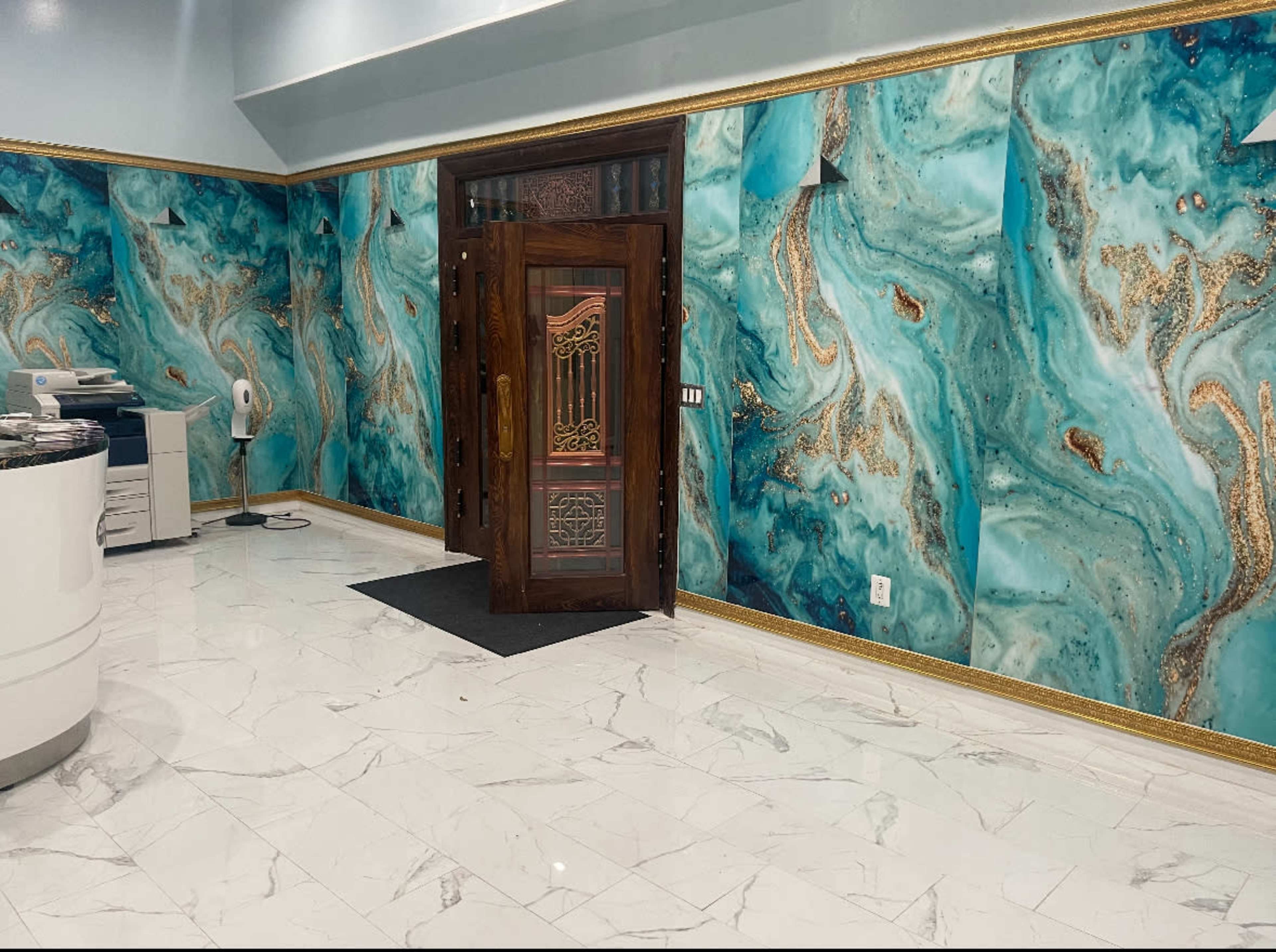 The image features a large entryway with intricate turquoise marble-patterned walls and a wooden door, complemented by glossy white marble flooring.