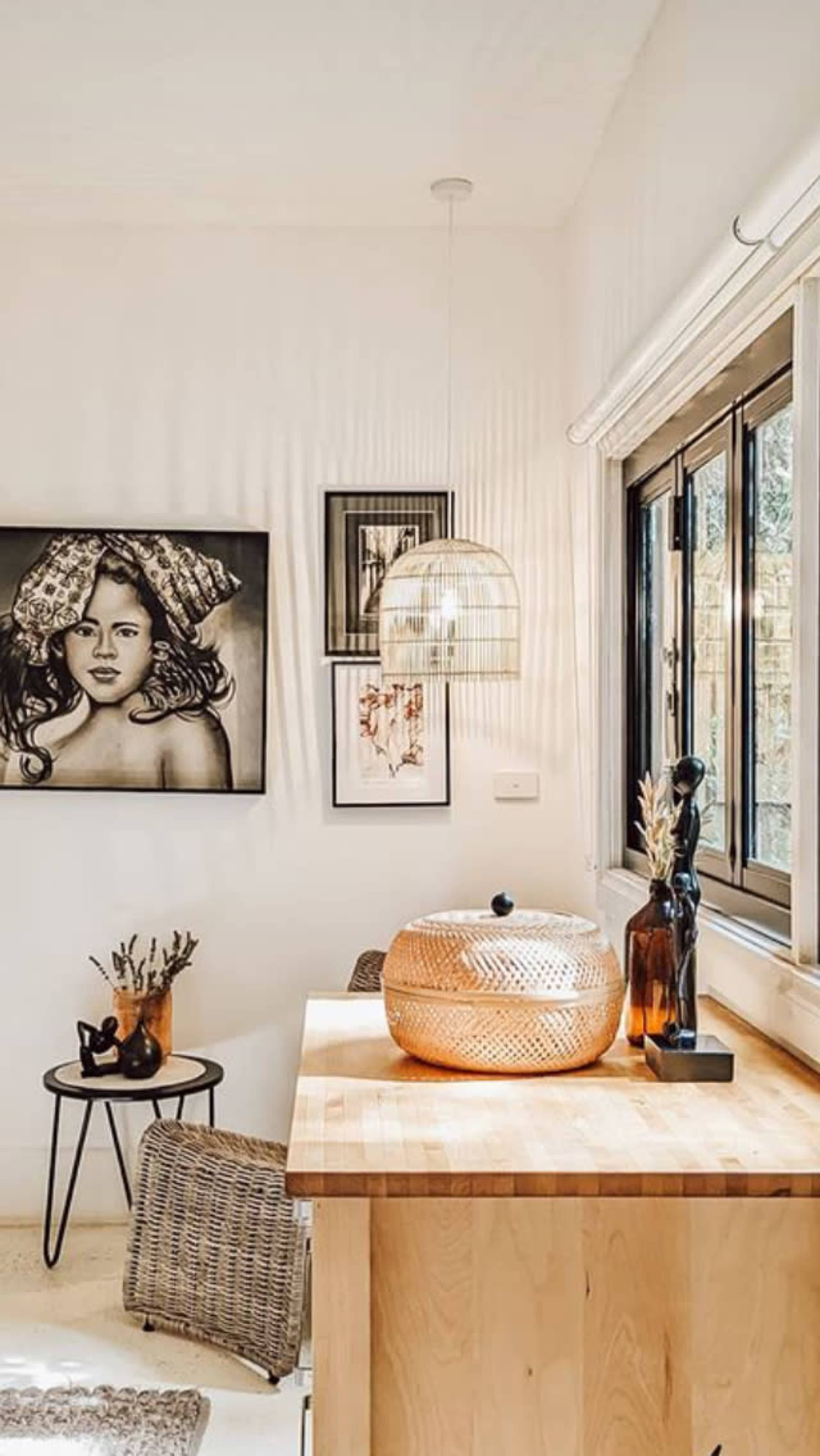 The image shows a contemporary kitchen corner featuring a wooden countertop, a decorative bowl, and artwork on the wall.