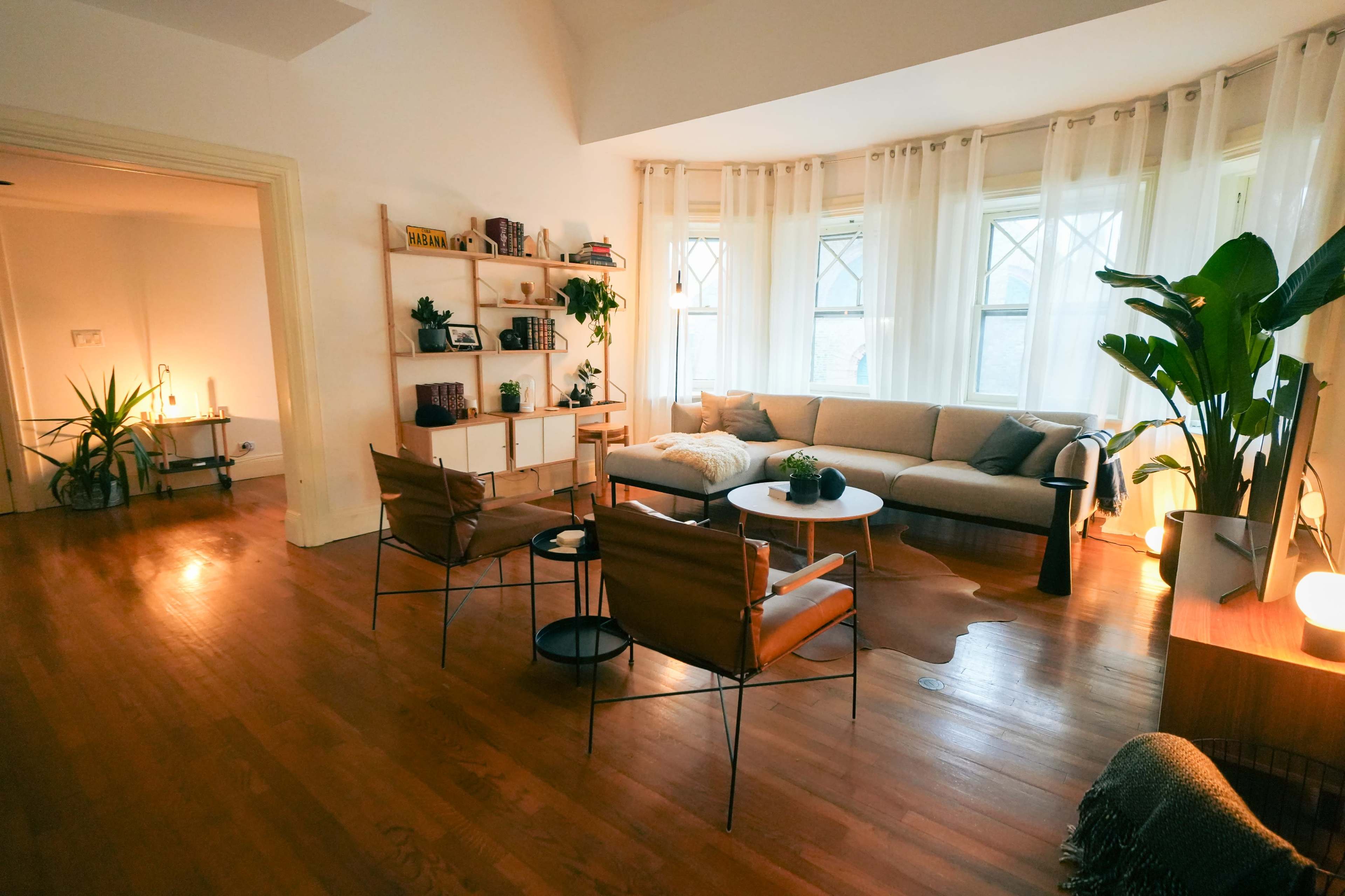 A cozy living room features a sectional sofa, wooden shelves with decor, and stylish seating around a circular coffee table.