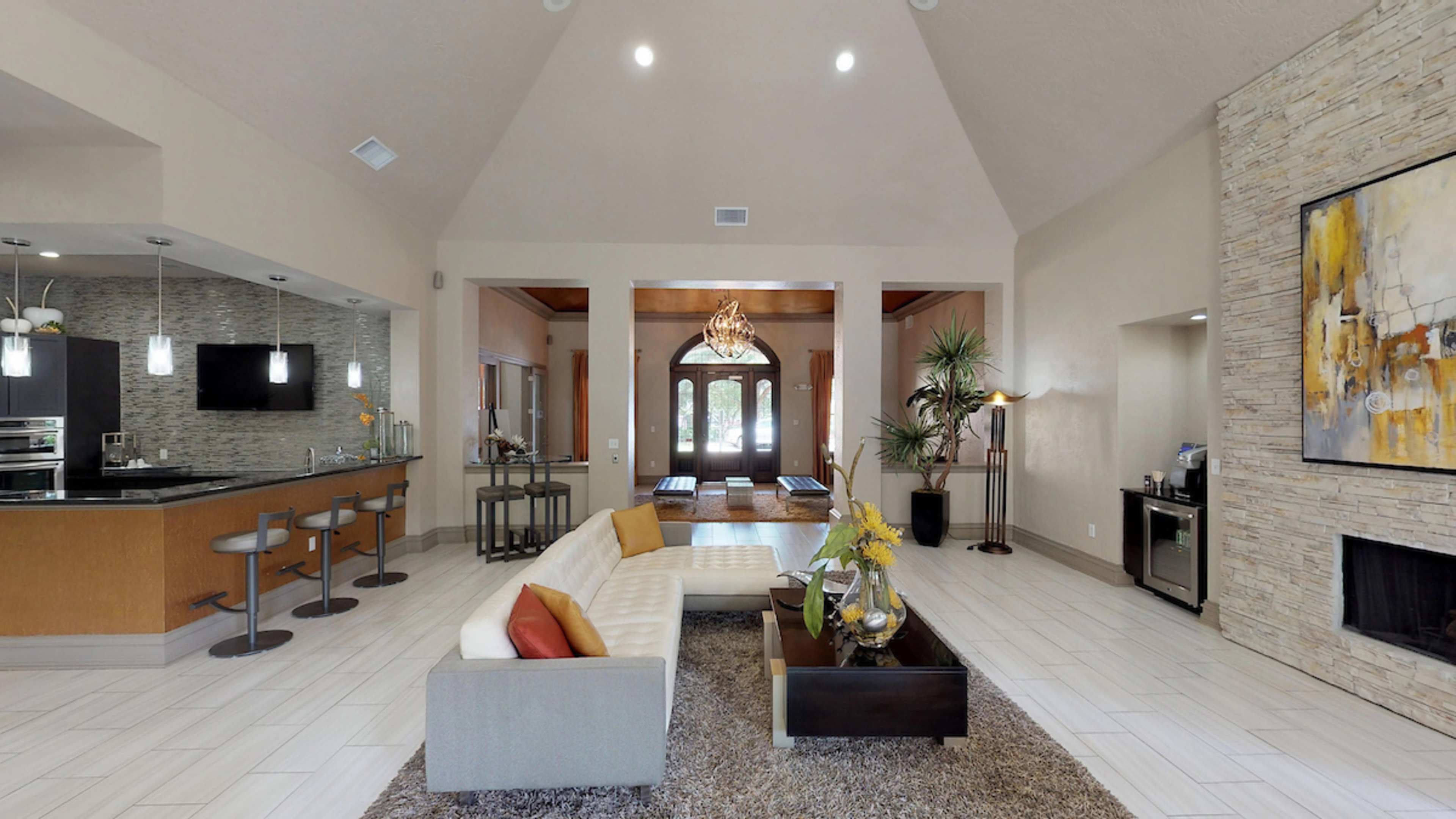 A spacious living room features a large sectional sofa, modern kitchen bar, and a decorative stone fireplace.