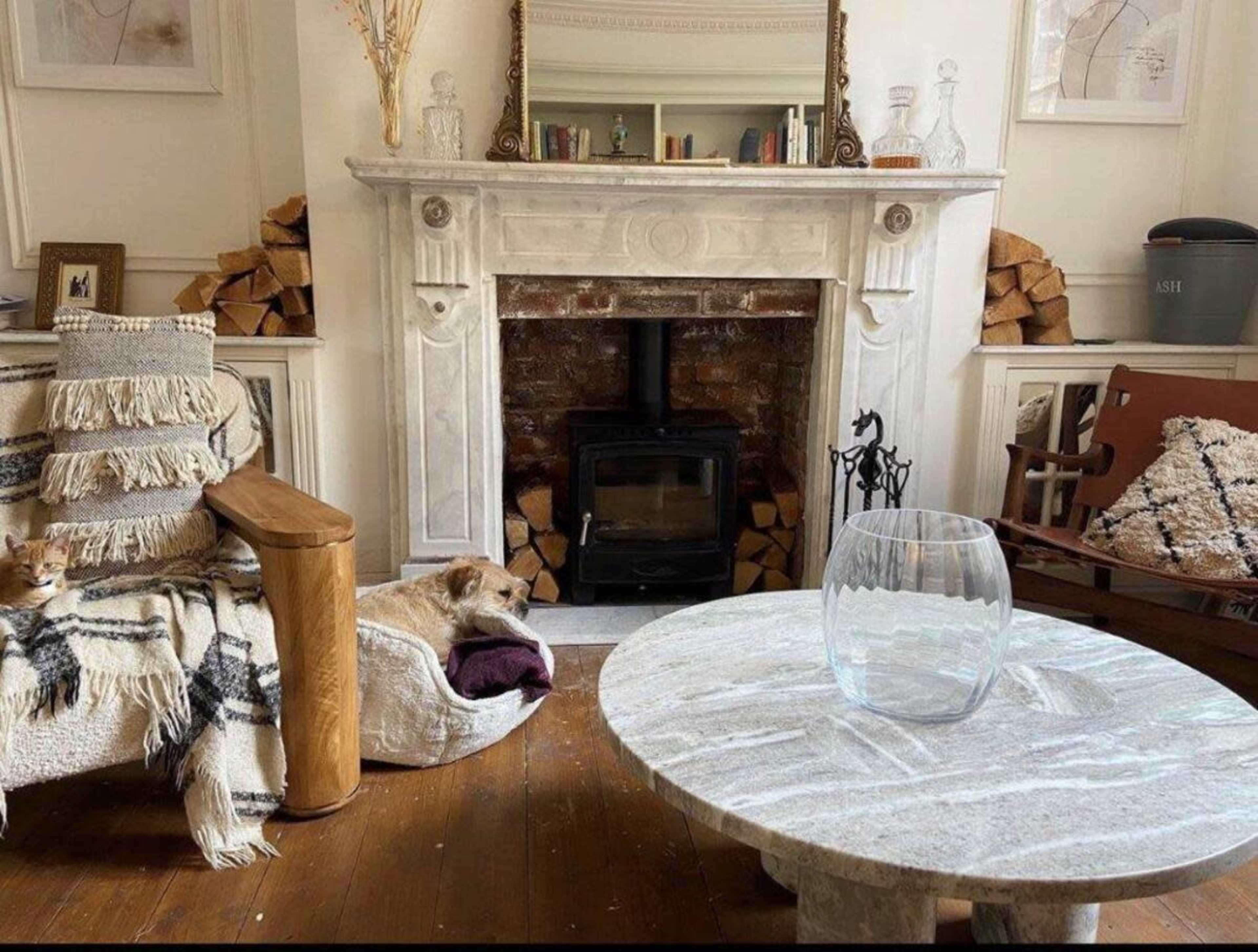 A cozy living room with a stone fireplace, a wooden coffee table, and a dog resting on a dog bed near the fireplace.