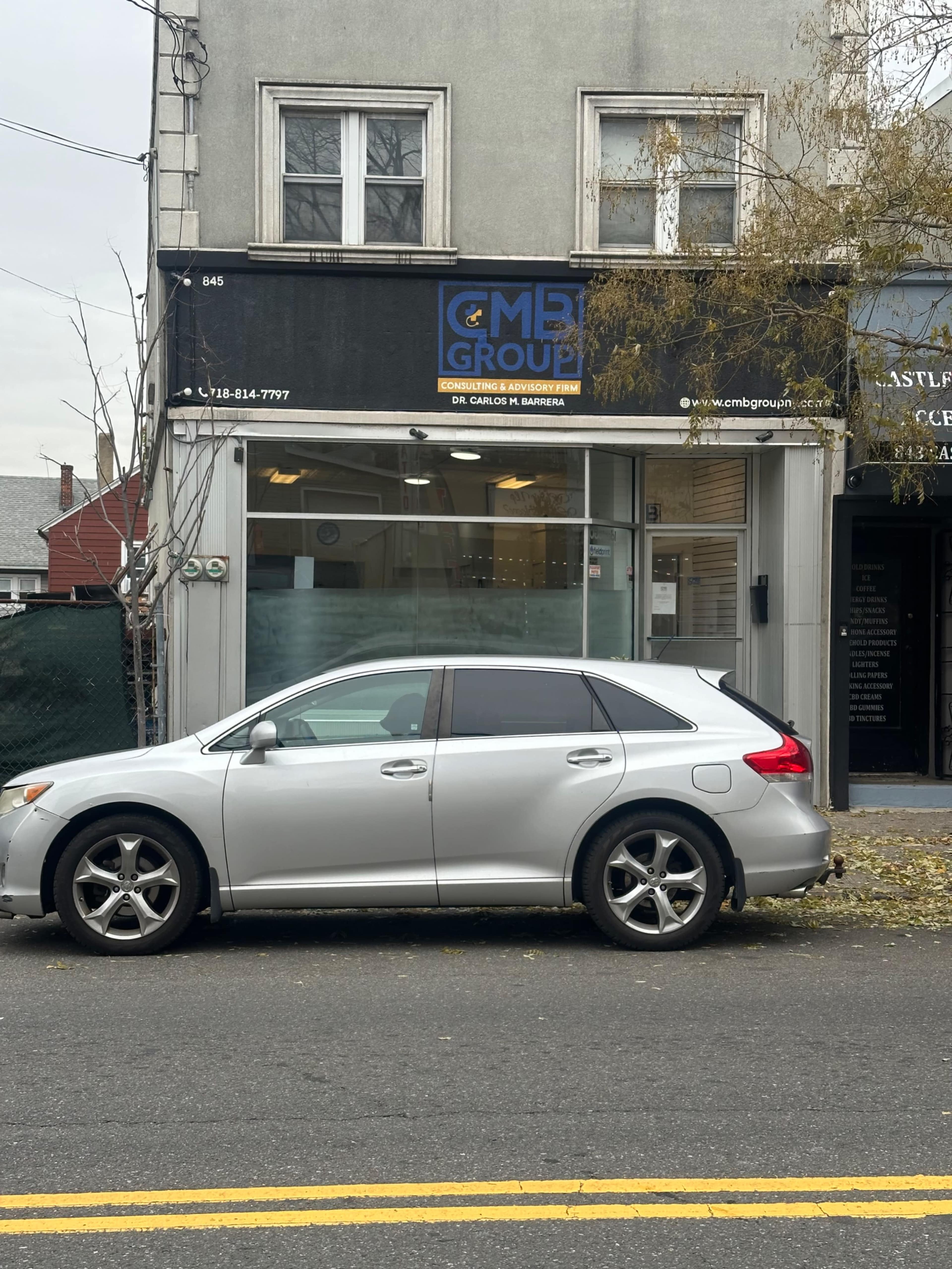 A silver SUV is parked in front of a commercial building that features a sign for CMB Group and Dr. Carlos R. Baez.