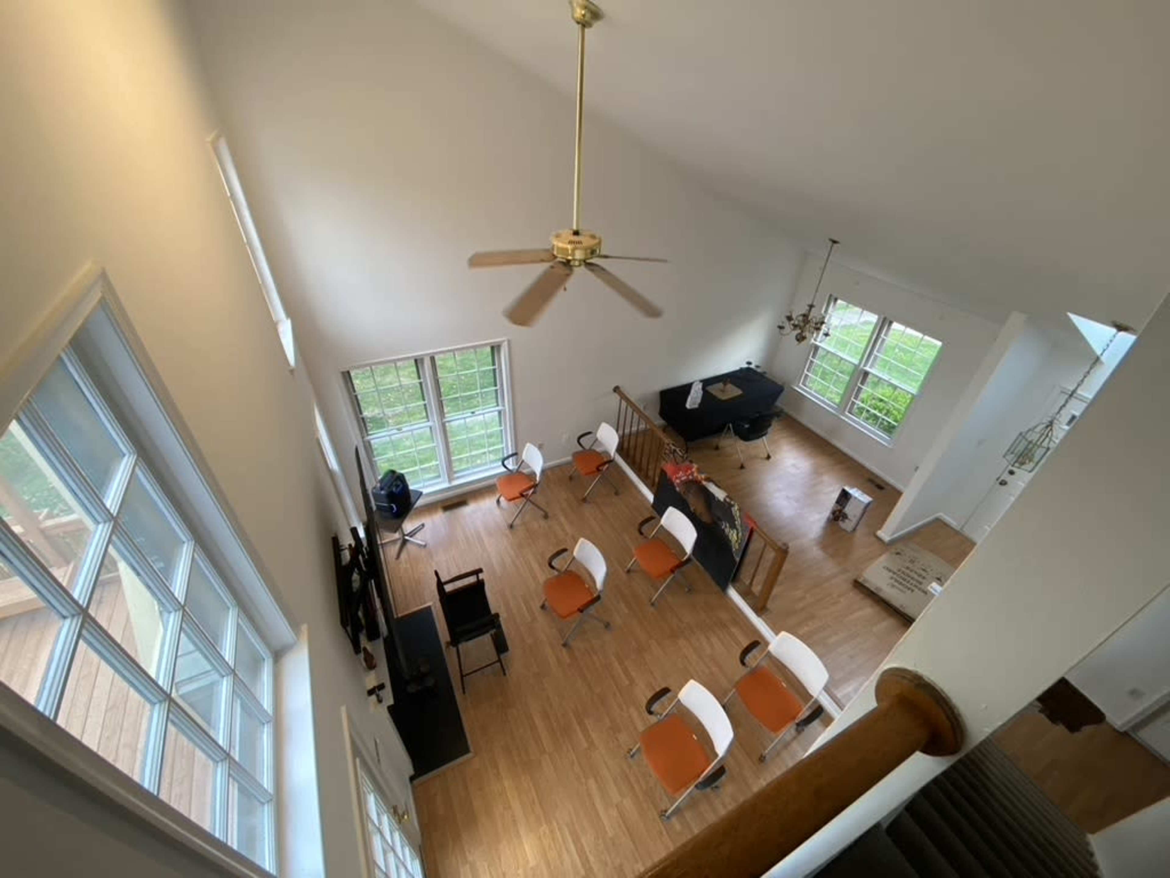 A spacious room features a high ceiling, large windows, a pool table, and several chairs arranged around a central table.