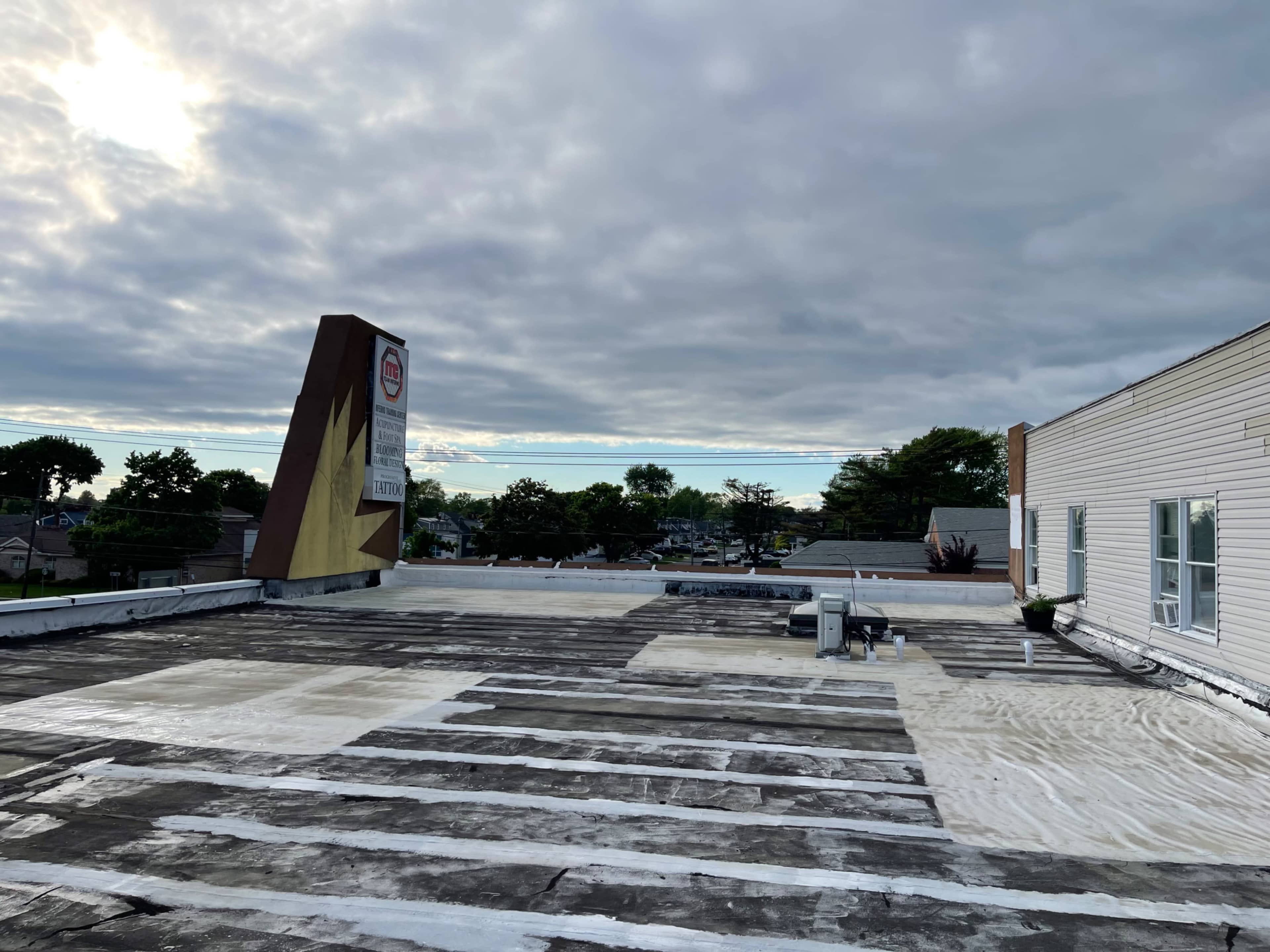 A flat rooftop with uneven patches and a cloudy sky in the background.