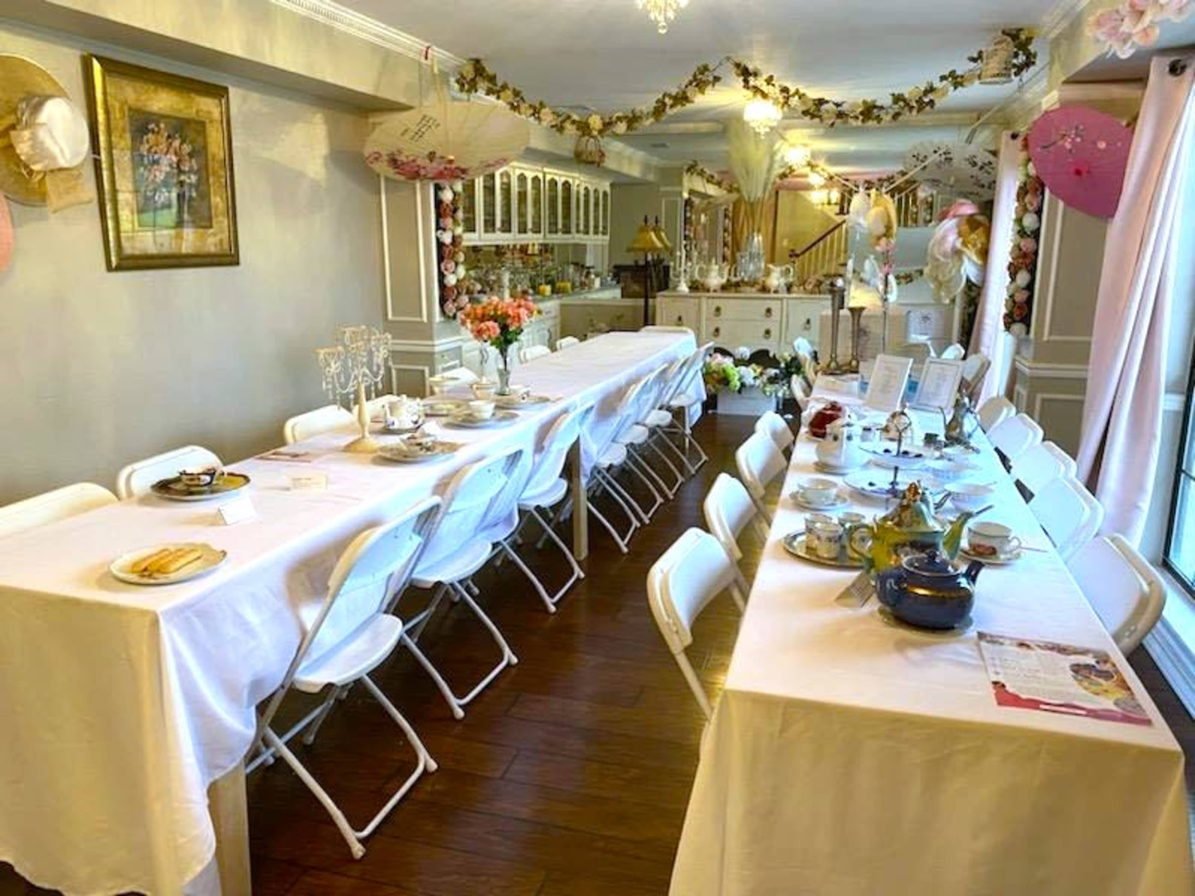 A long dining table set with dishes and decorations is arranged in a room adorned with flowers and decorative elements.