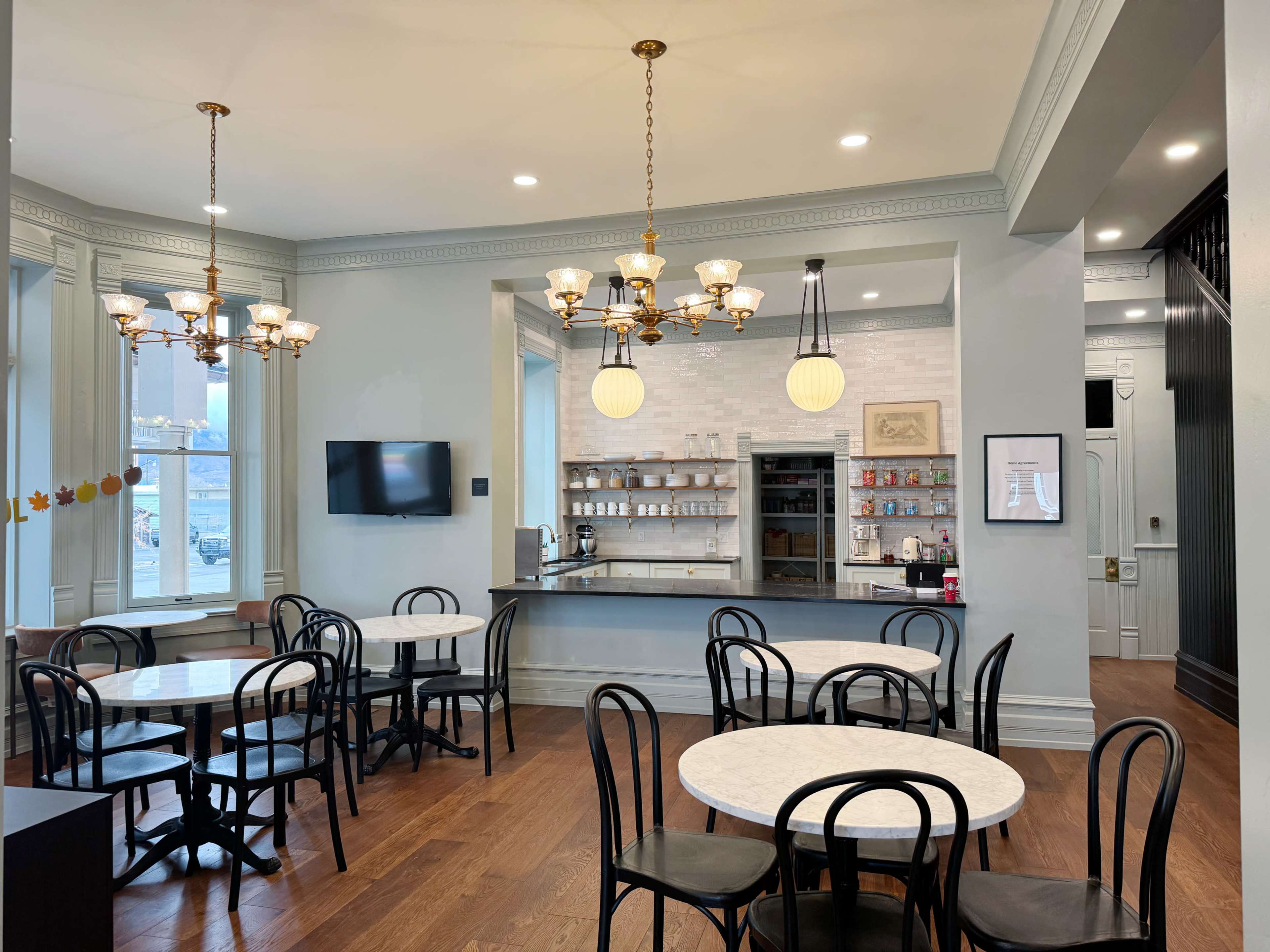 A bright café interior features marble tables and black chairs, with decorative lighting and a service counter in the background.