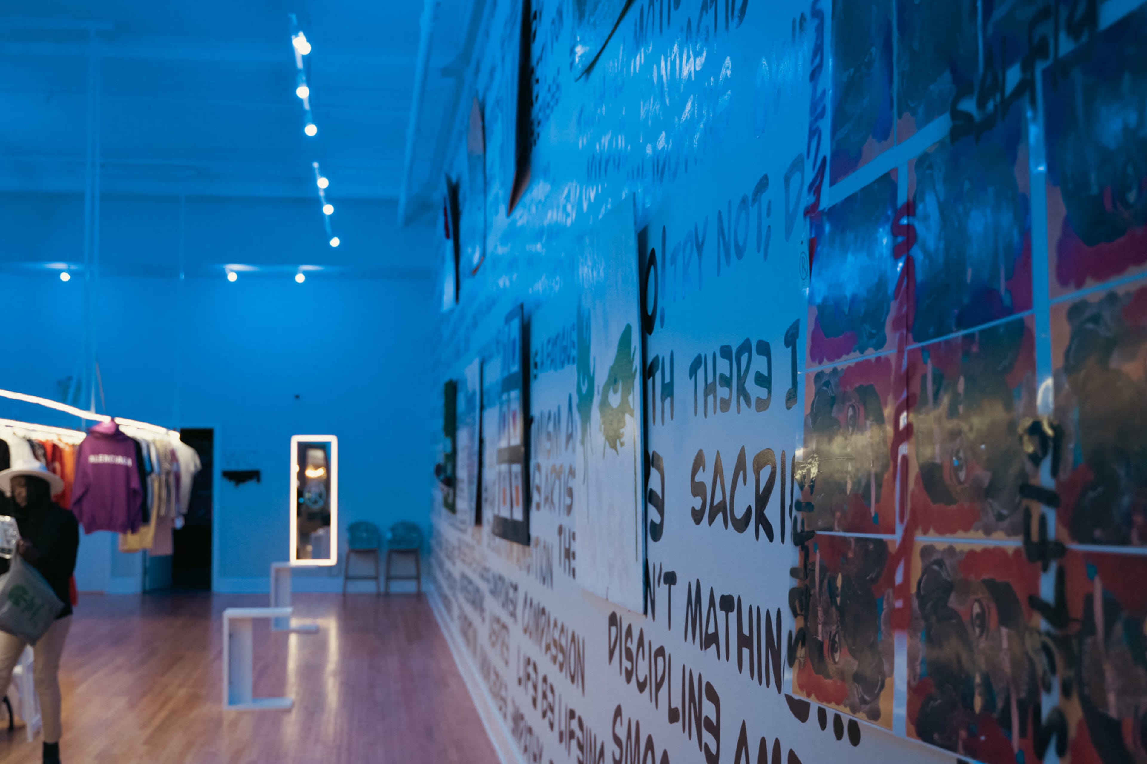 An art gallery with walls covered in colorful text and images, and a doorway leading to another room.