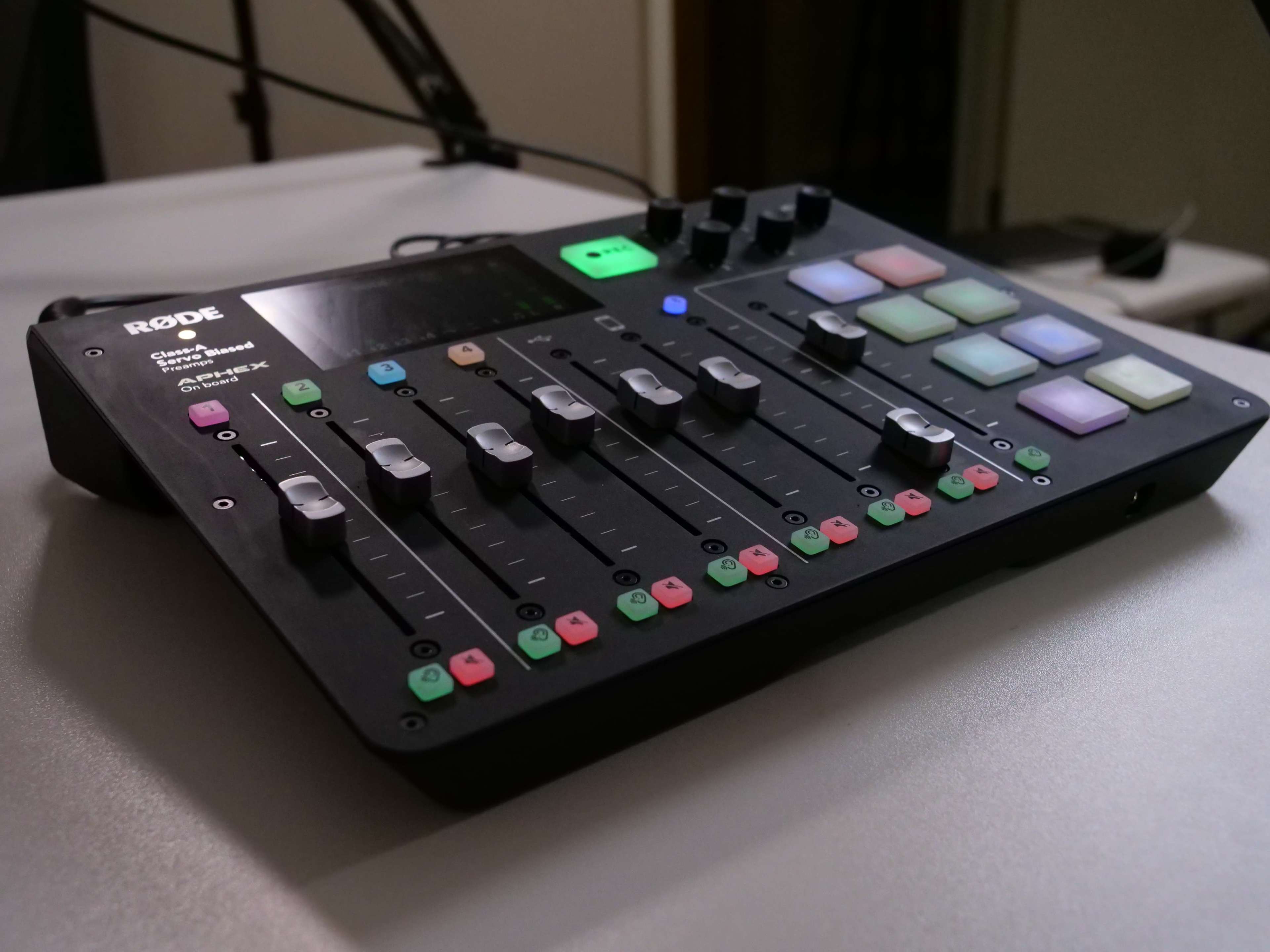 A Rode audio interface with multiple faders, buttons, and LED indicators.