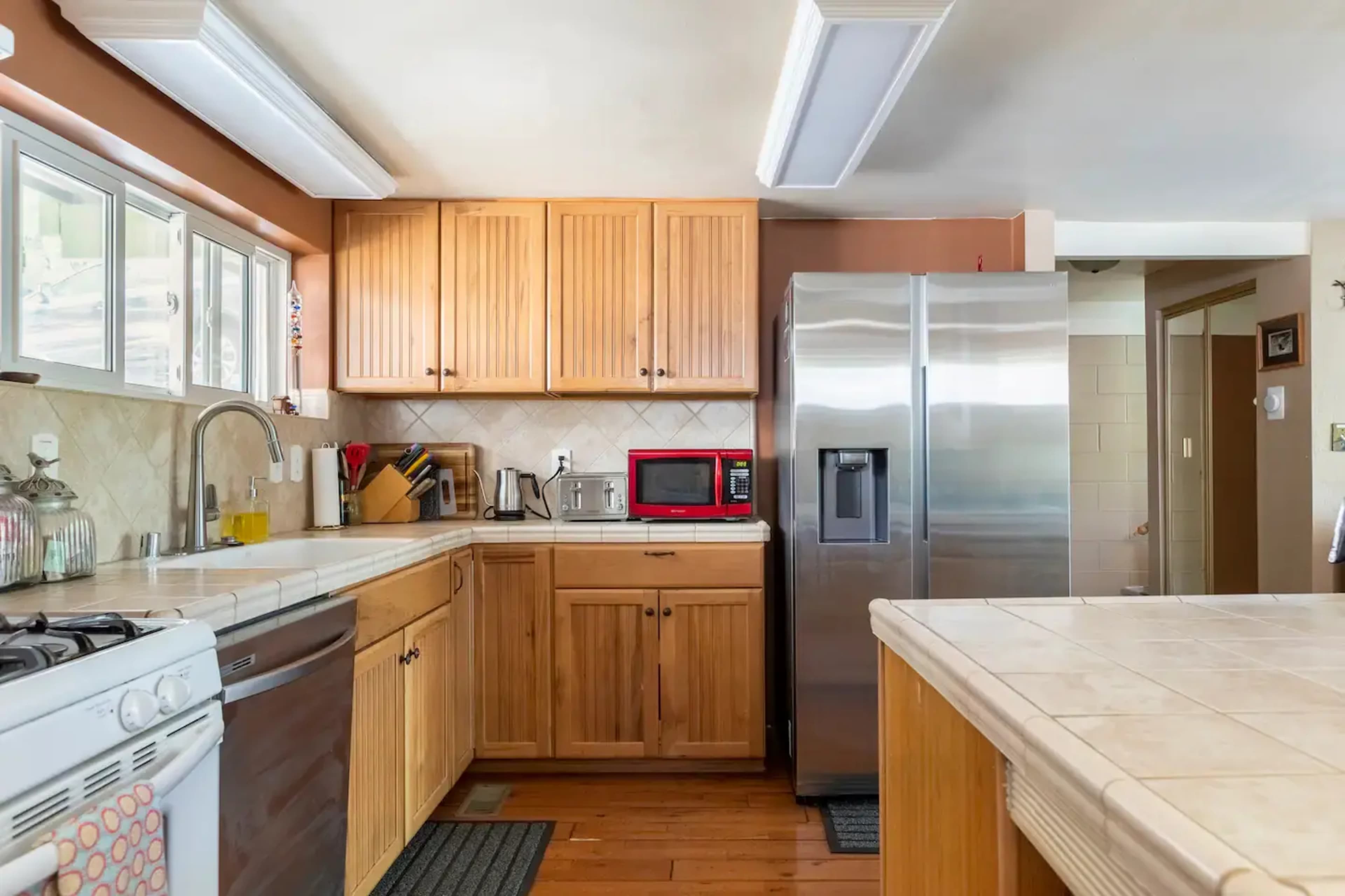 A kitchen with wooden cabinetry, stainless steel appliances, and a tiled countertop.