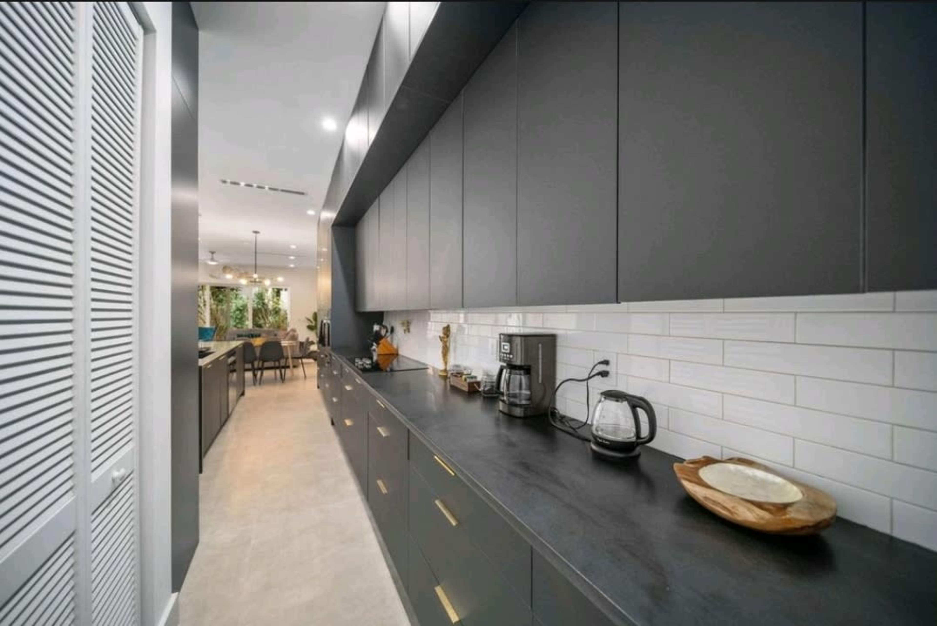 A modern kitchen features dark cabinetry, a long countertop, and stainless steel appliances along one side.