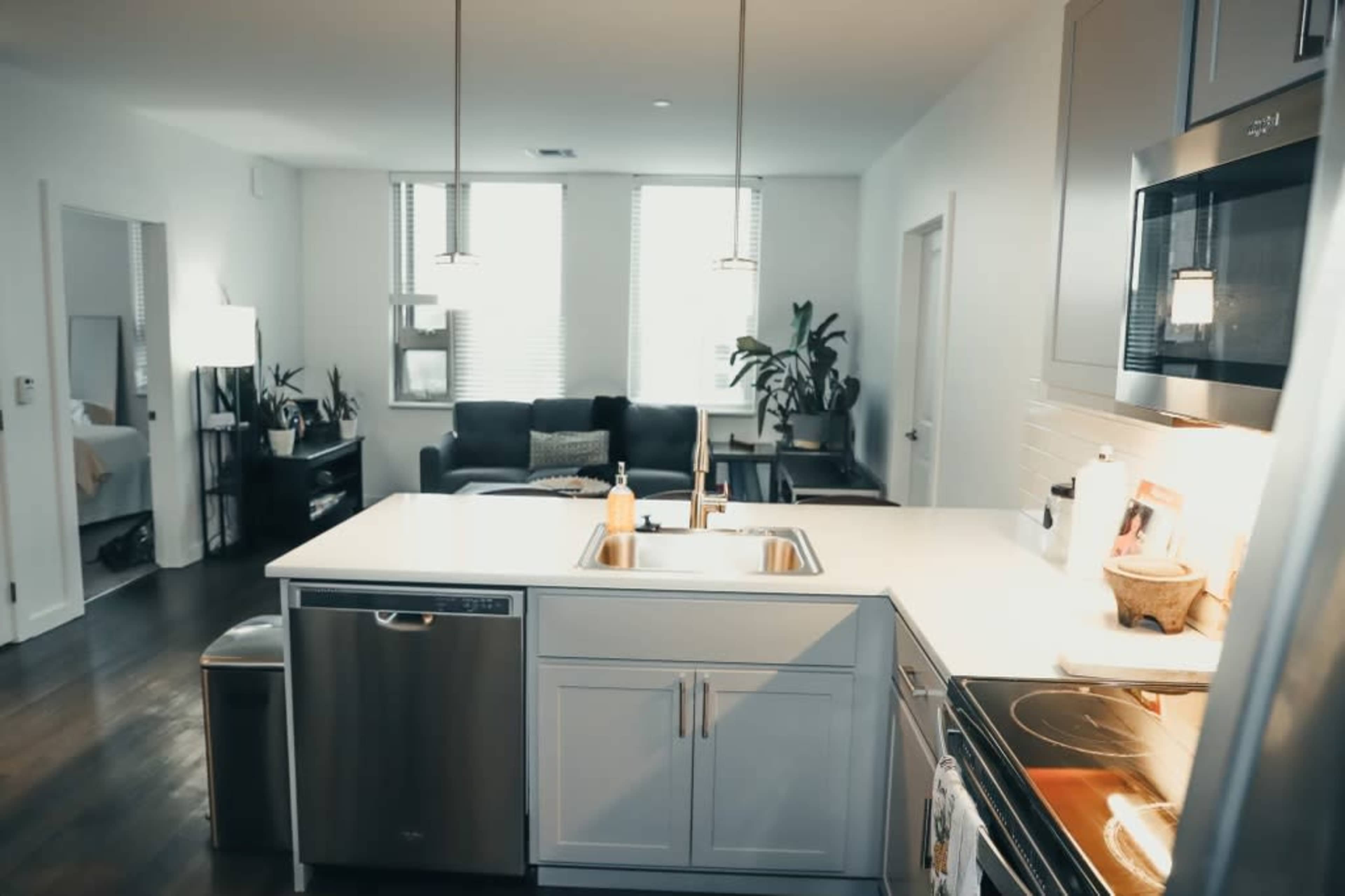 A modern kitchen with a central island, stainless steel appliances, and a living area visible in the background.