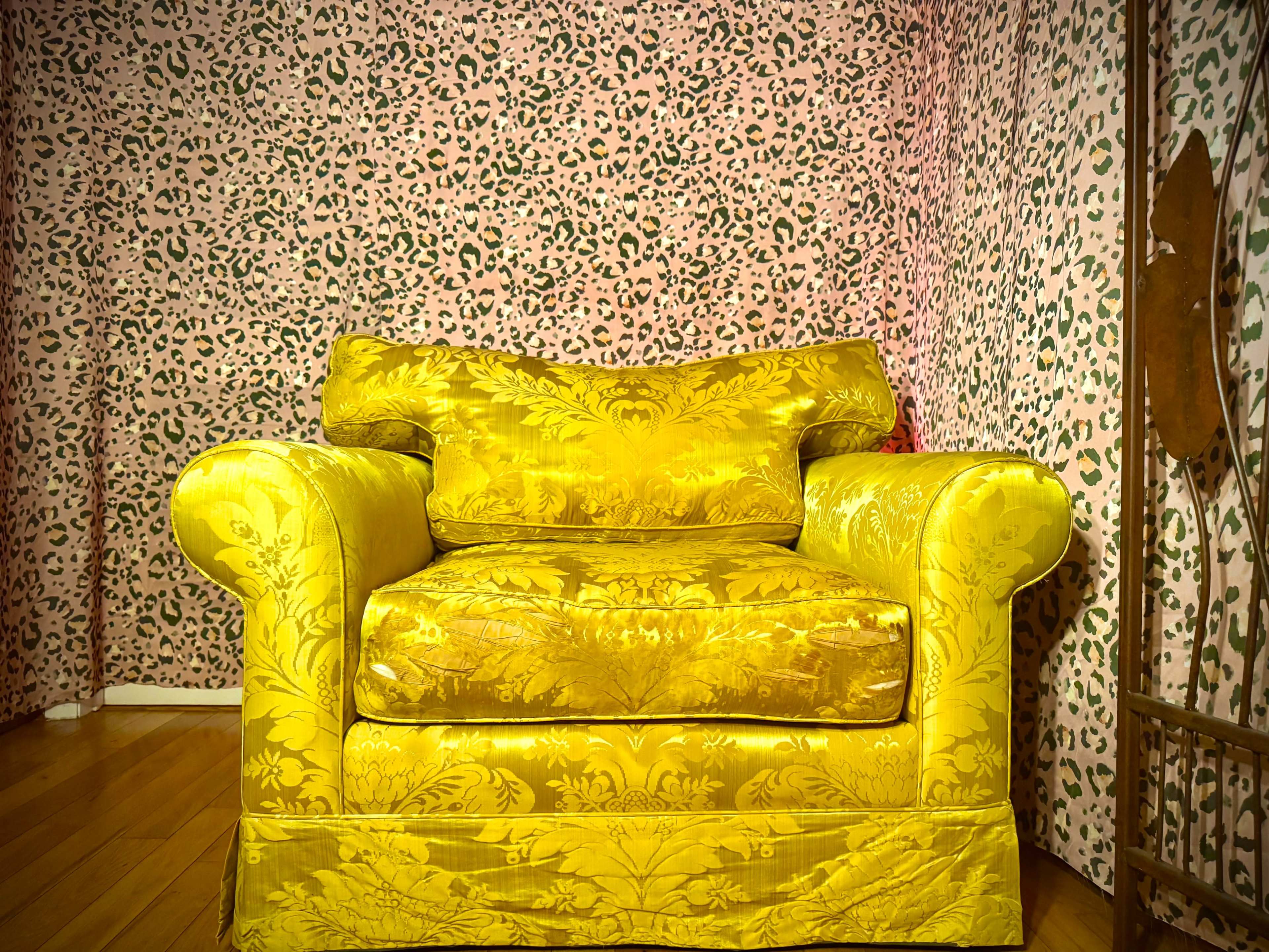 The image features a yellow upholstered armchair against a patterned pink and green leopard print background.