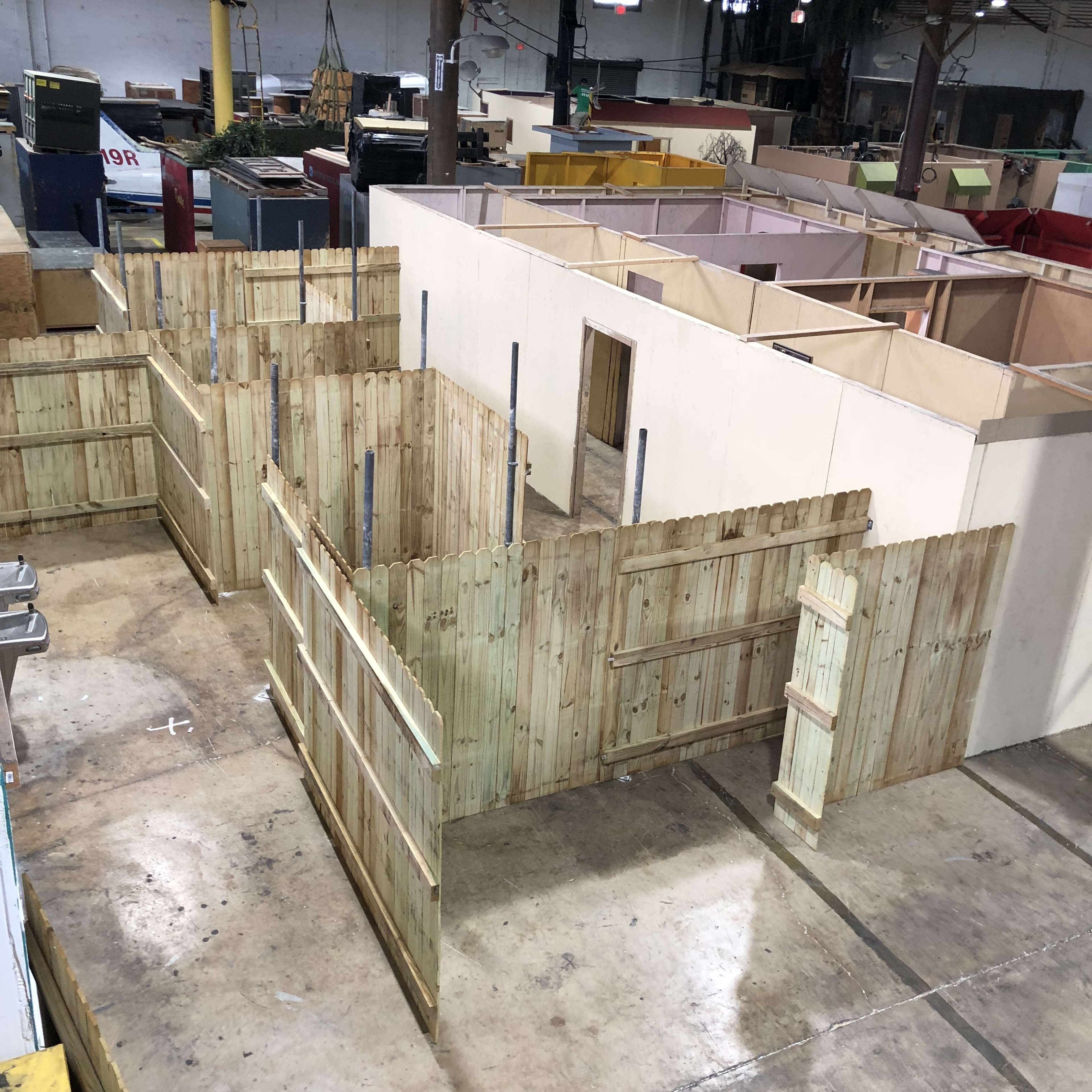 The image shows a large open space with several wooden fence-like structures and walls arranged to create enclosed areas.