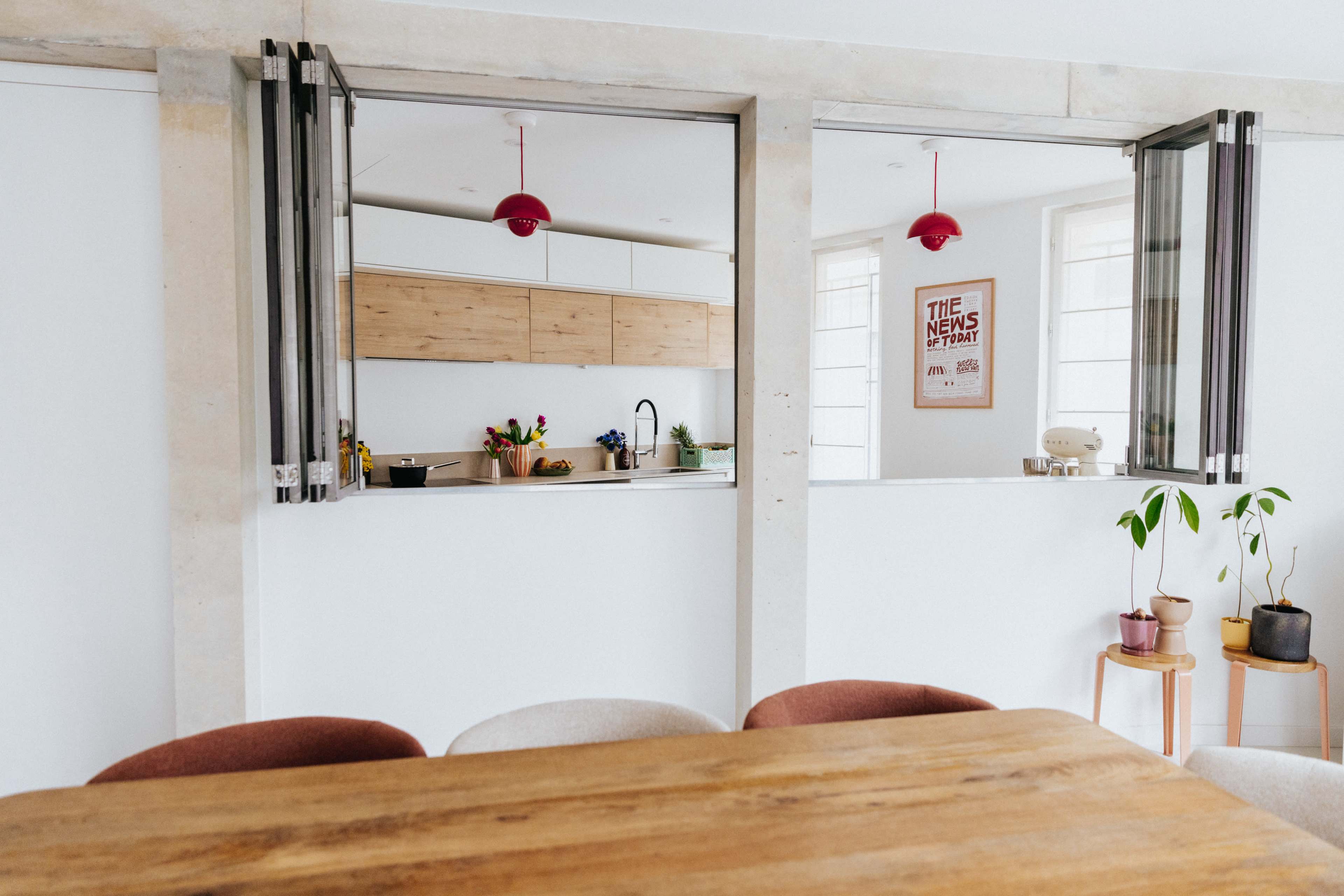 A kitchen with light wood cabinets and a dining area featuring a wooden table and colorful pendant lights.