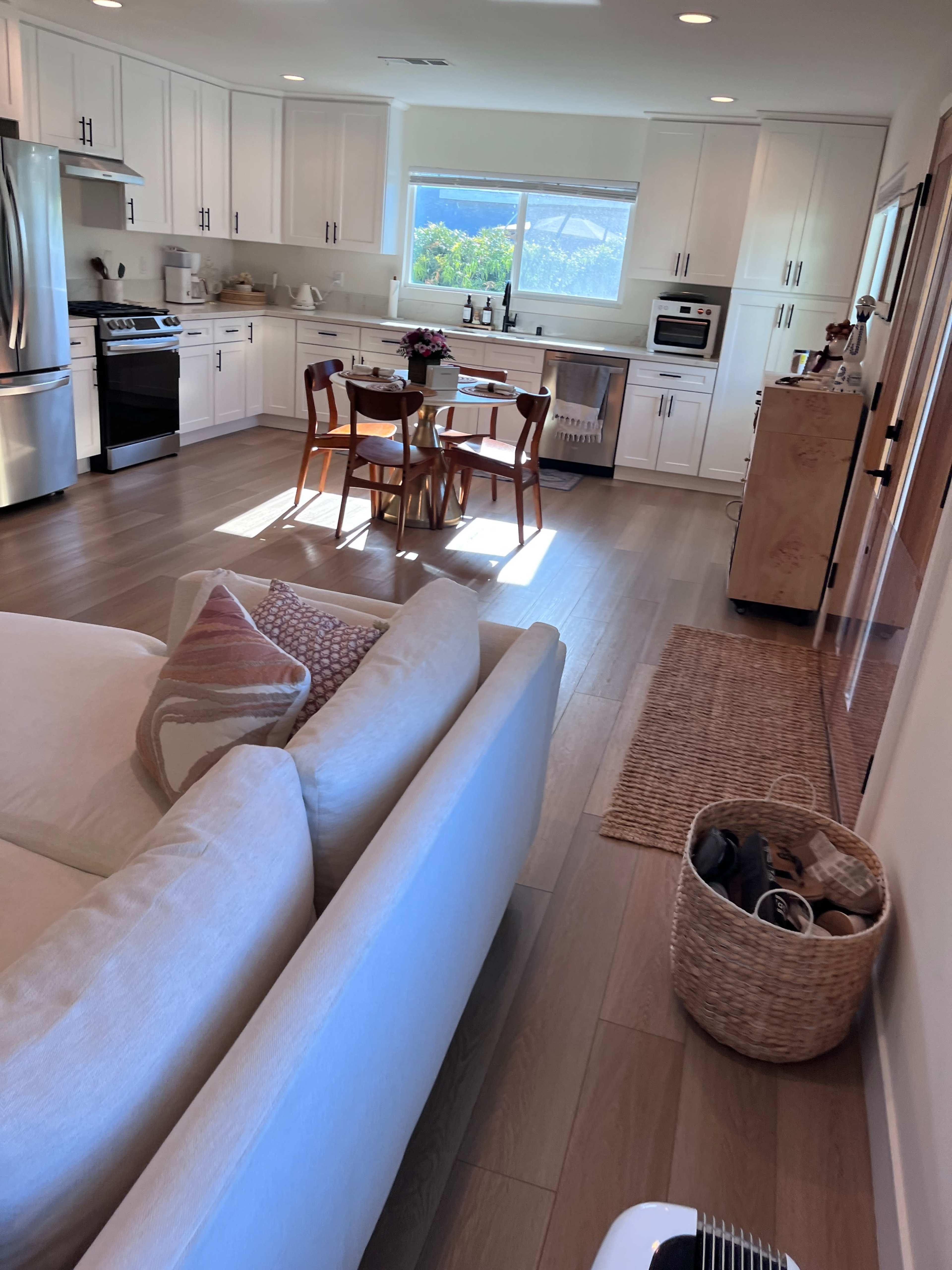 A modern kitchen and dining area features a light-filled space with sleek cabinetry, a dining table, and a comfortable sofa.