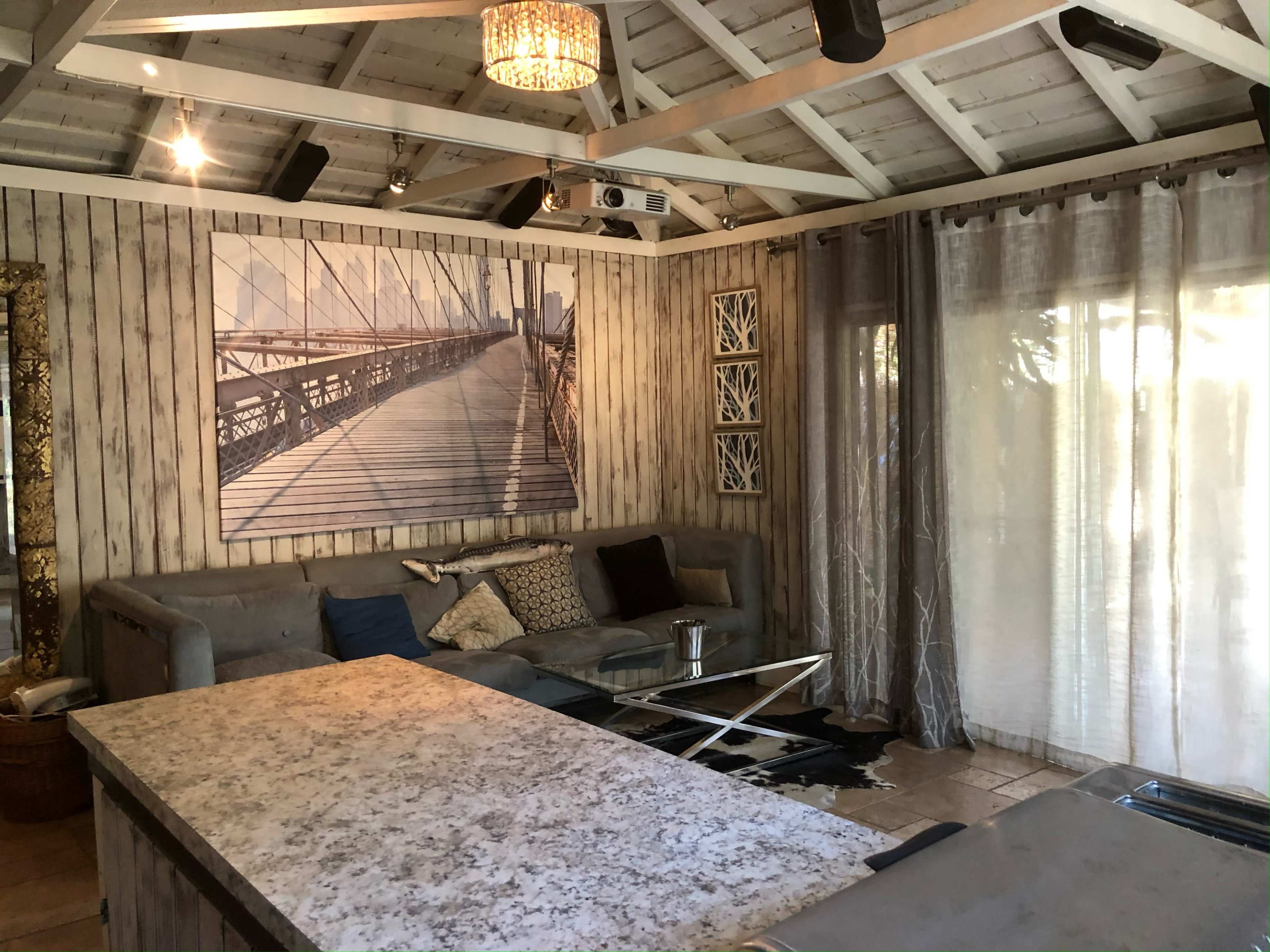 The image shows a rustic living room with a large bridge photograph on the wall and a quartz-topped table in the center.