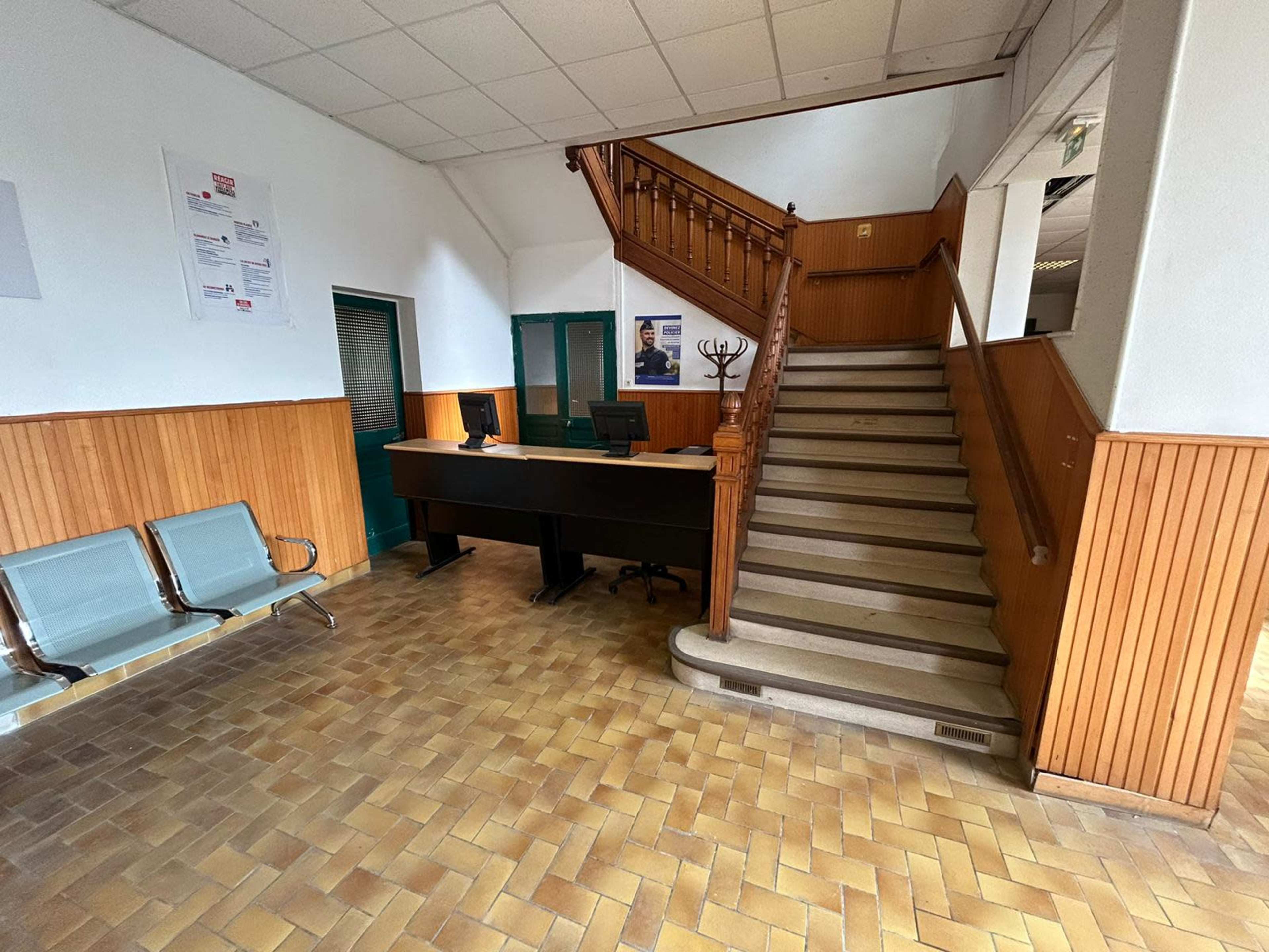 An interior lobby with a reception desk, seating area, and a staircase leading to an upper level.