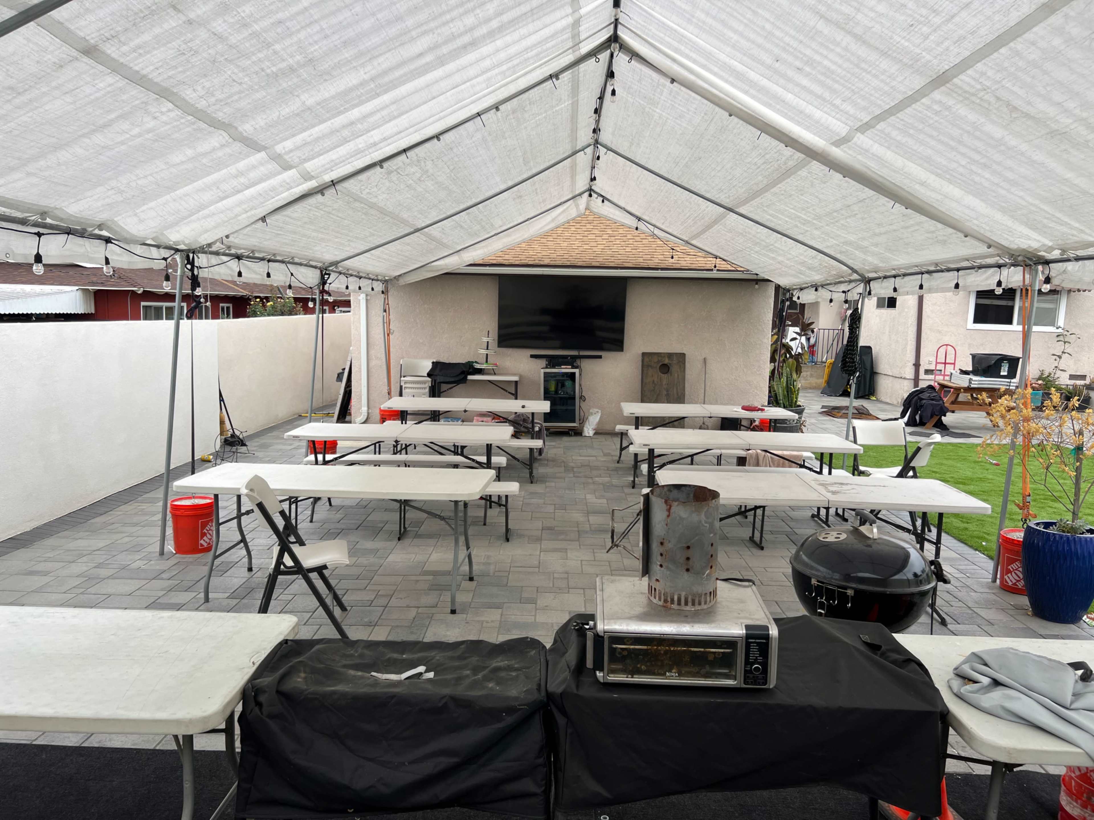 A large open tent with multiple tables and a cooking area set up in a paved outdoor space.