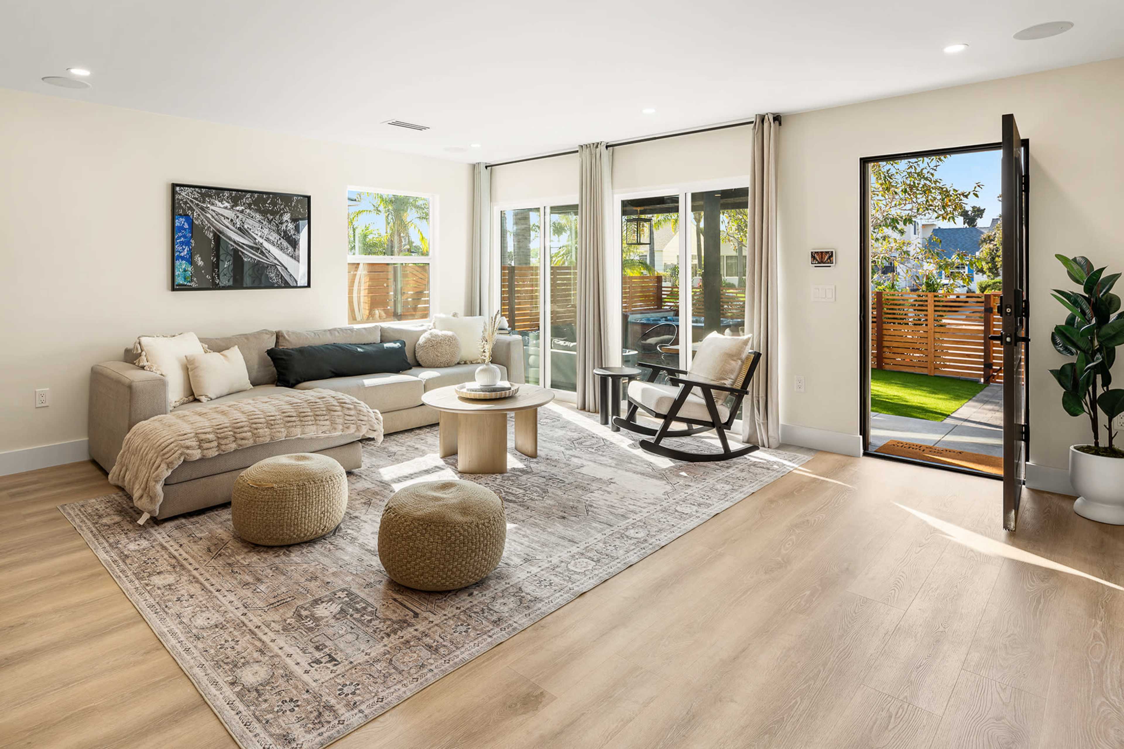 The living room features a modern sofa, a circular coffee table, a rocking chair, and large glass doors that open to an outdoor area.