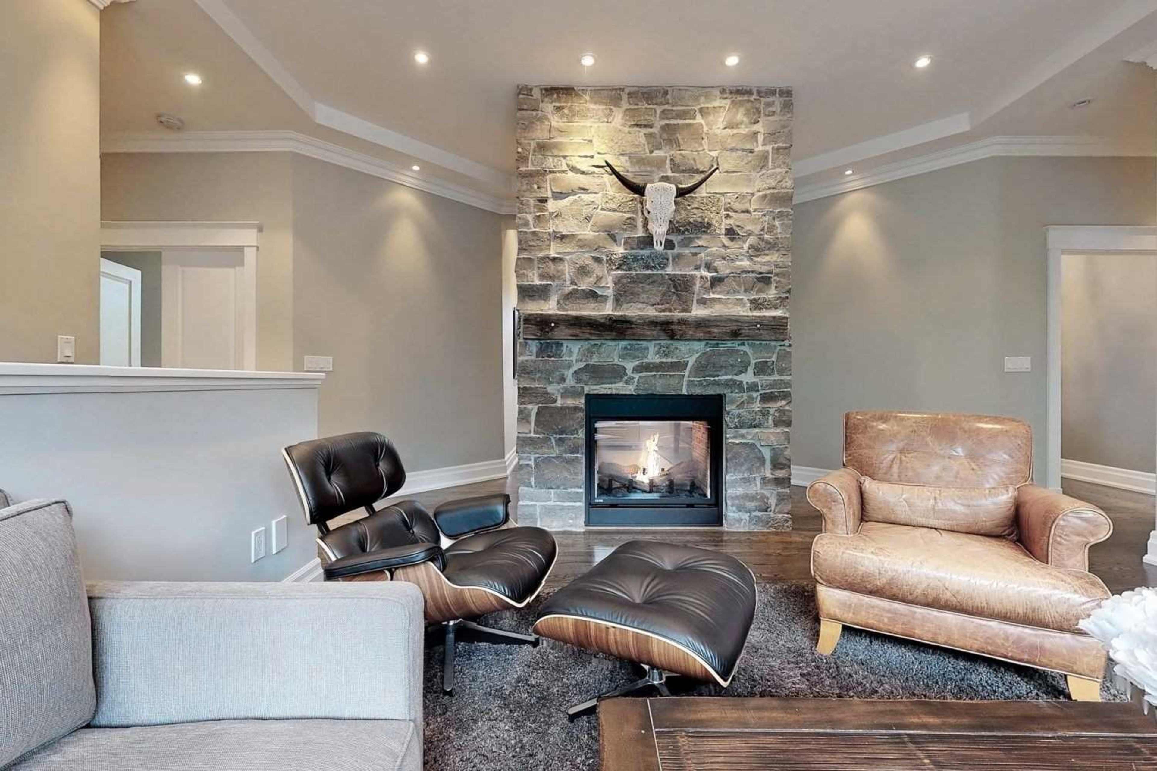 A modern living room features a stone fireplace with an antler decor piece above it, complemented by leather and upholstered seating.