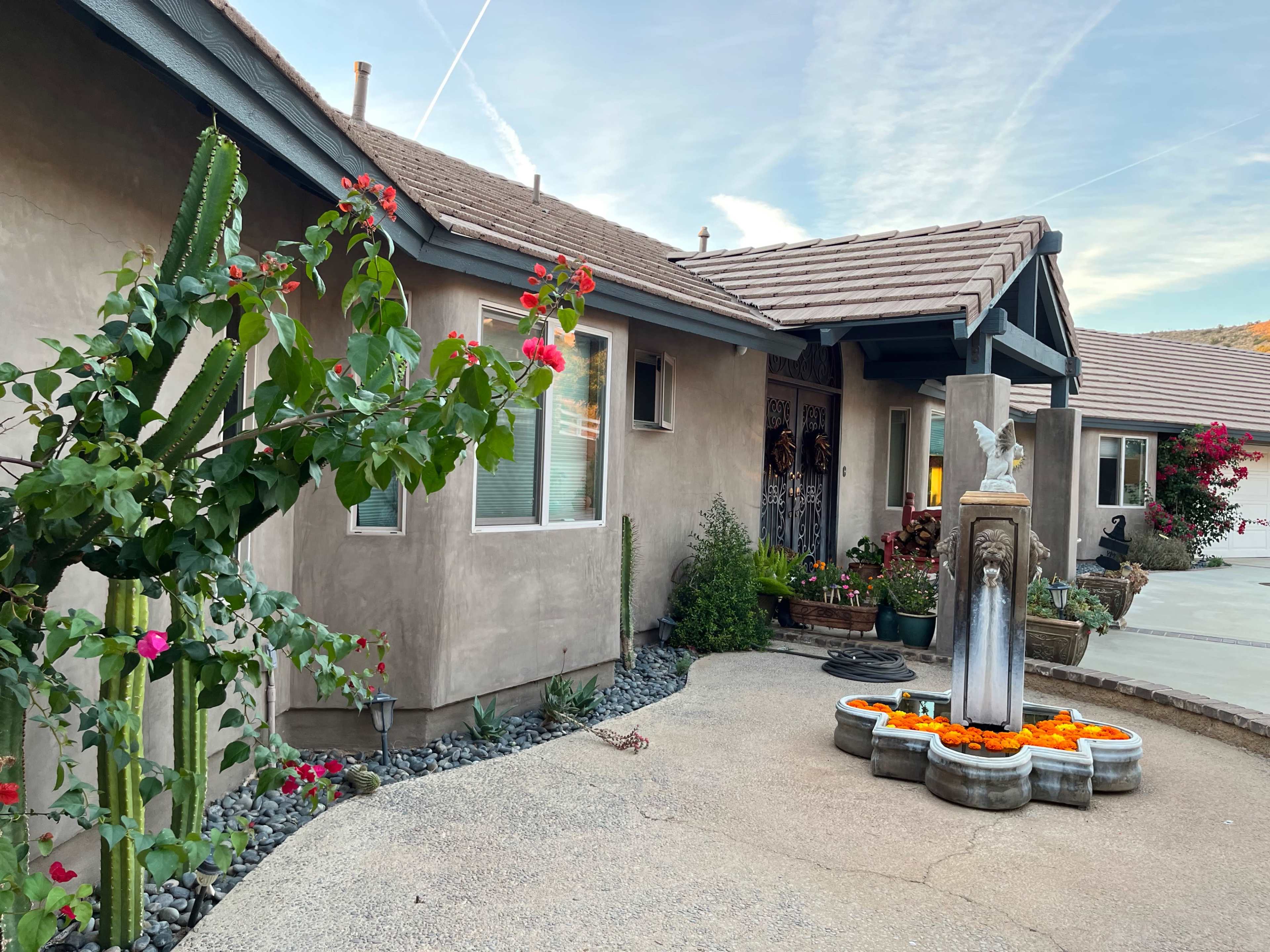 The image shows a well-maintained house with a courtyard featuring a decorative fountain surrounded by plants and flowers.