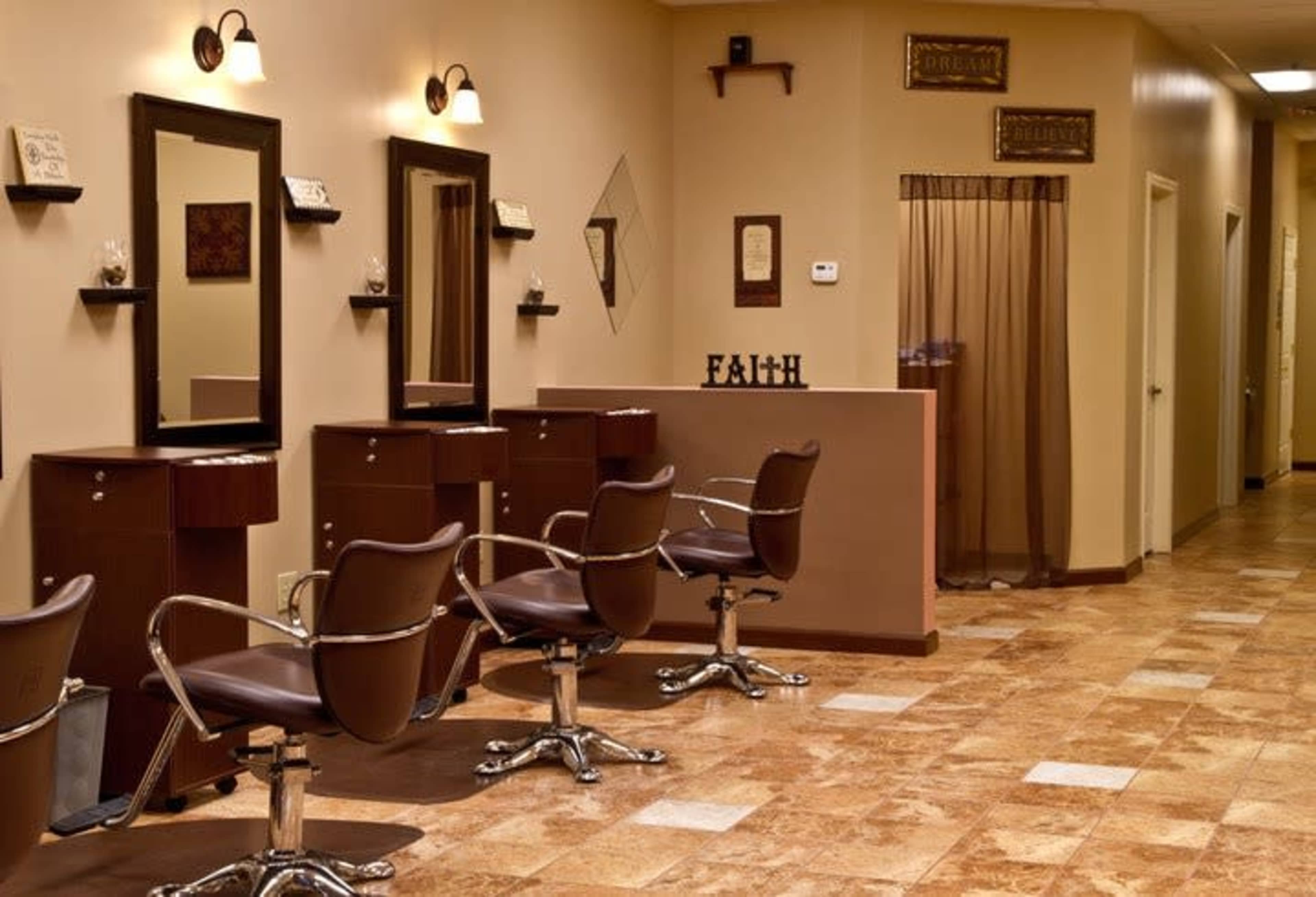 The image shows a hair salon interior with several styling stations, each featuring a mirror and a chair, and warm-toned walls.