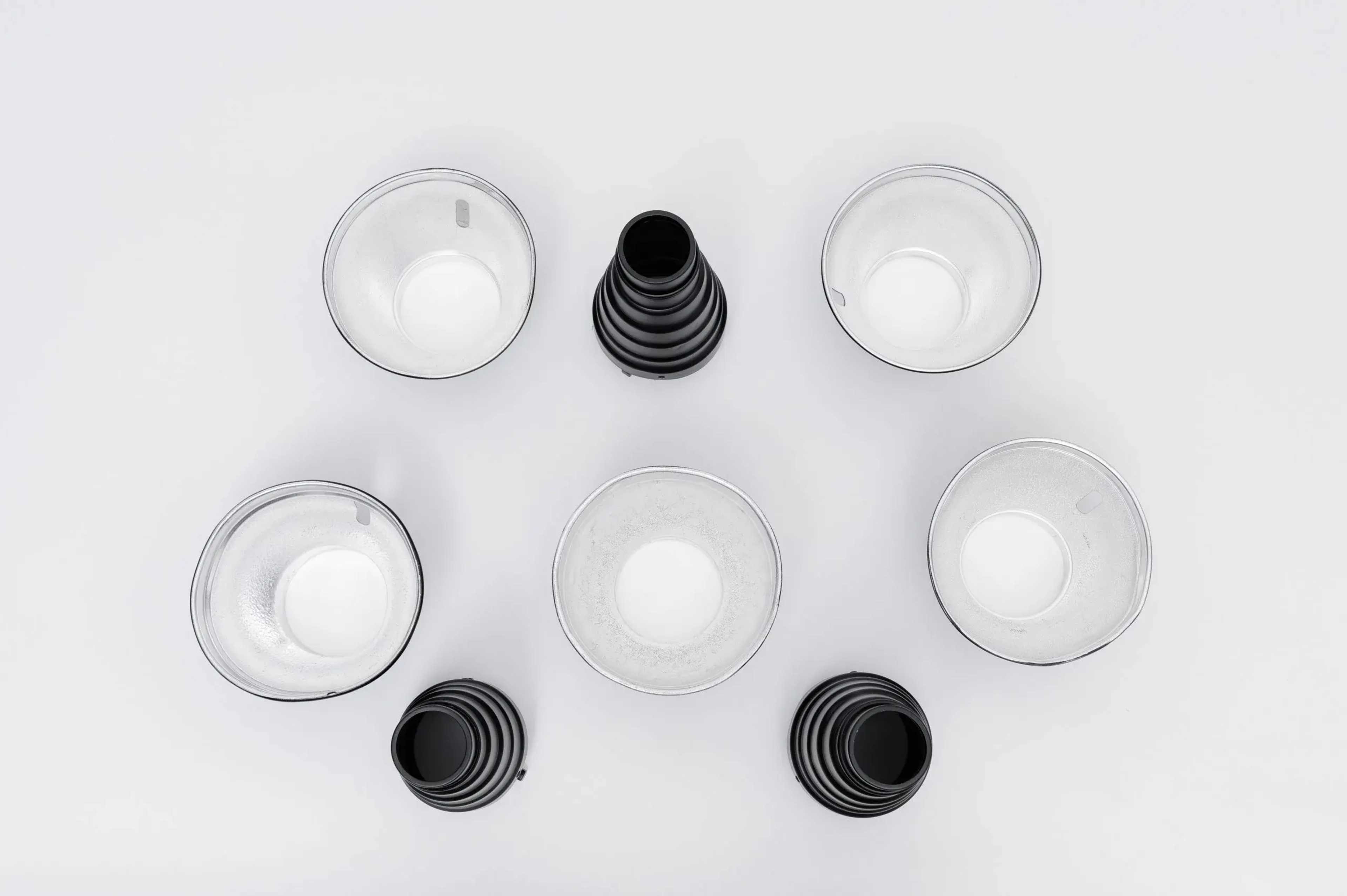 The image shows a symmetrical arrangement of clear cups and a funnel on a white background.